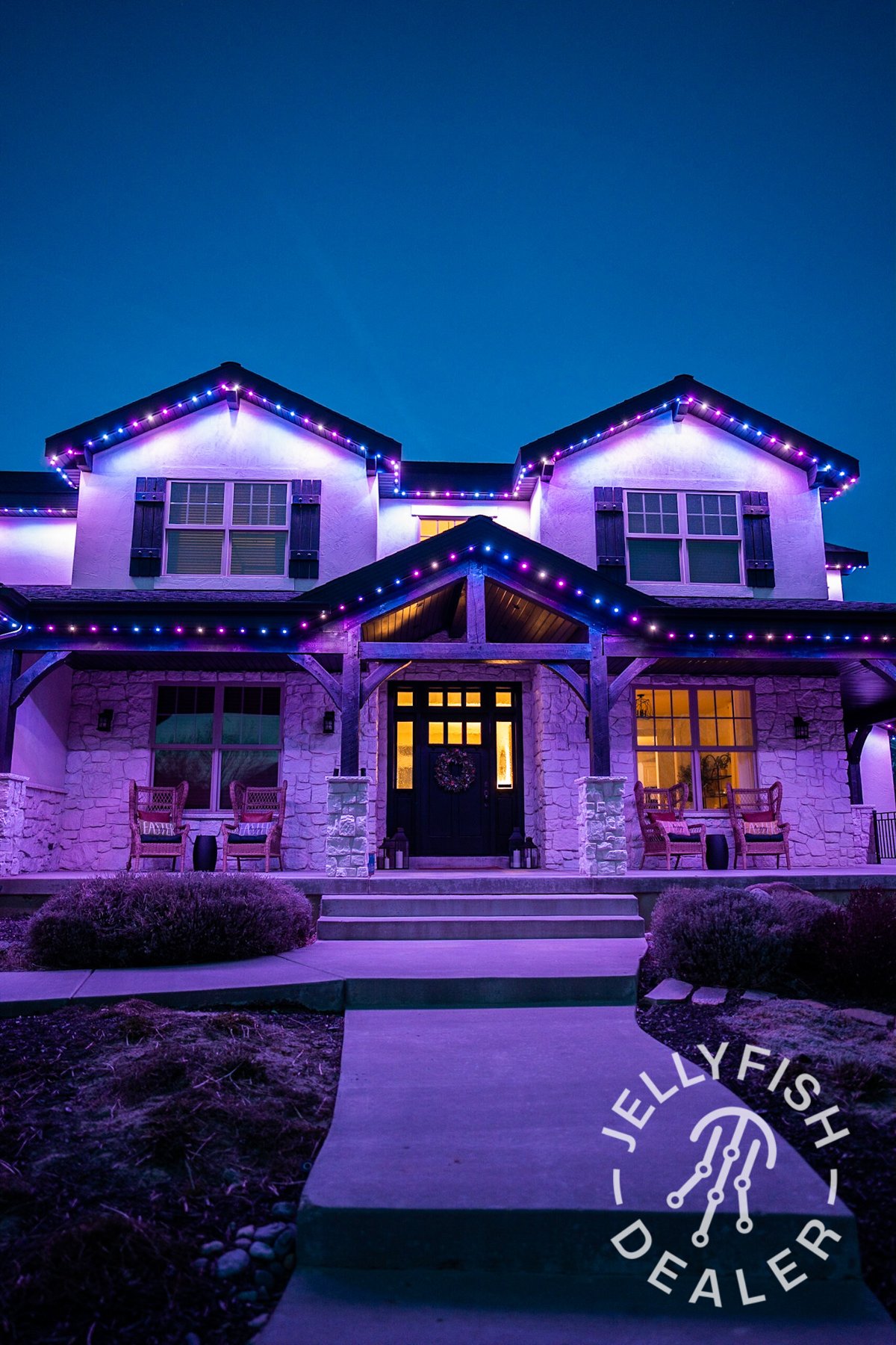 Purple and pink roofline lights on a two-story porch-front home.