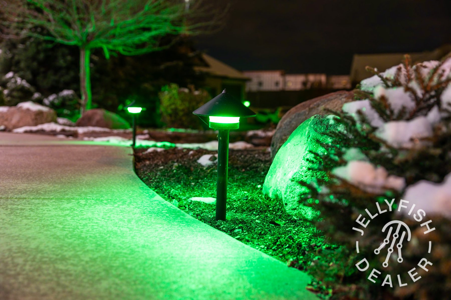 Green pathway lights beside a planted garden bed.