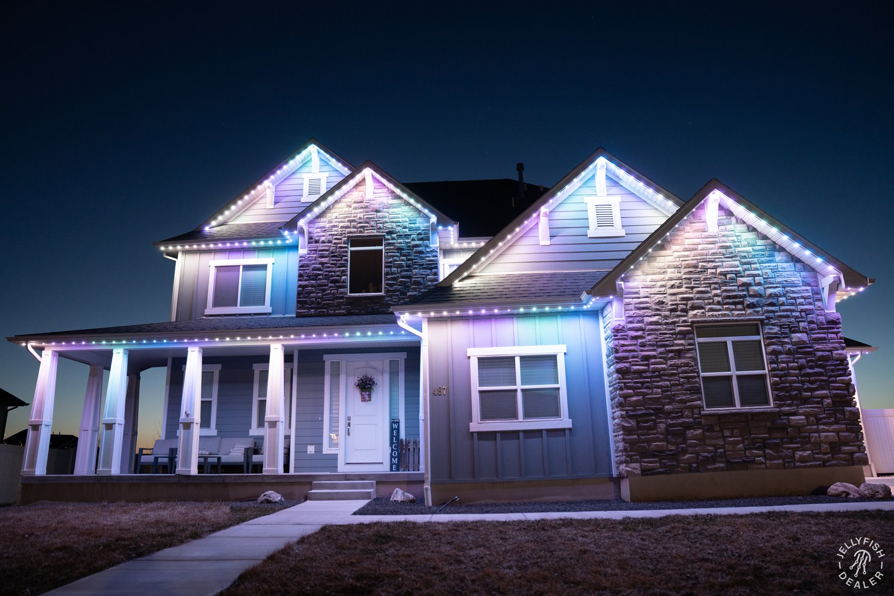 Pale blue and pink lights on a stone and siding home.