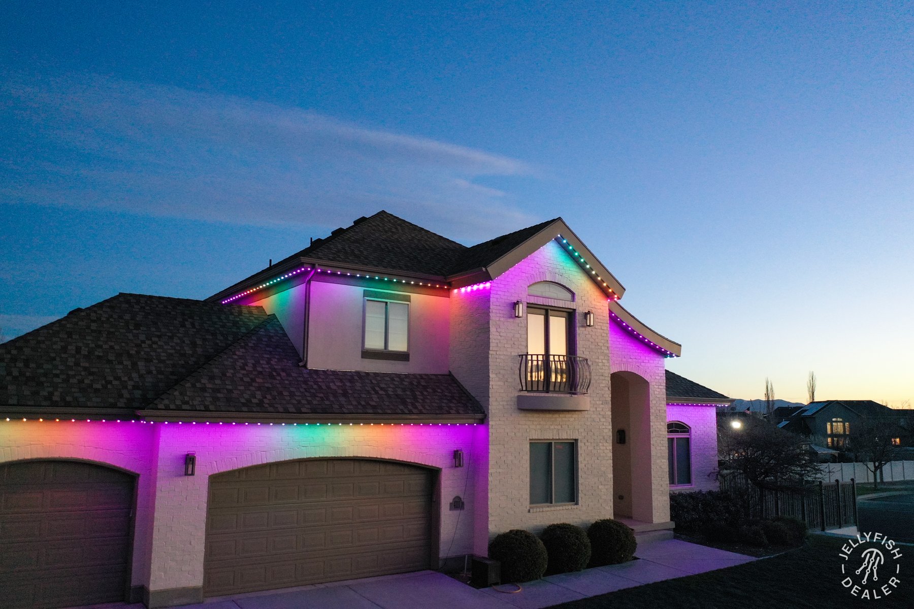 Rainbow lighting along a two-story home at dusk.