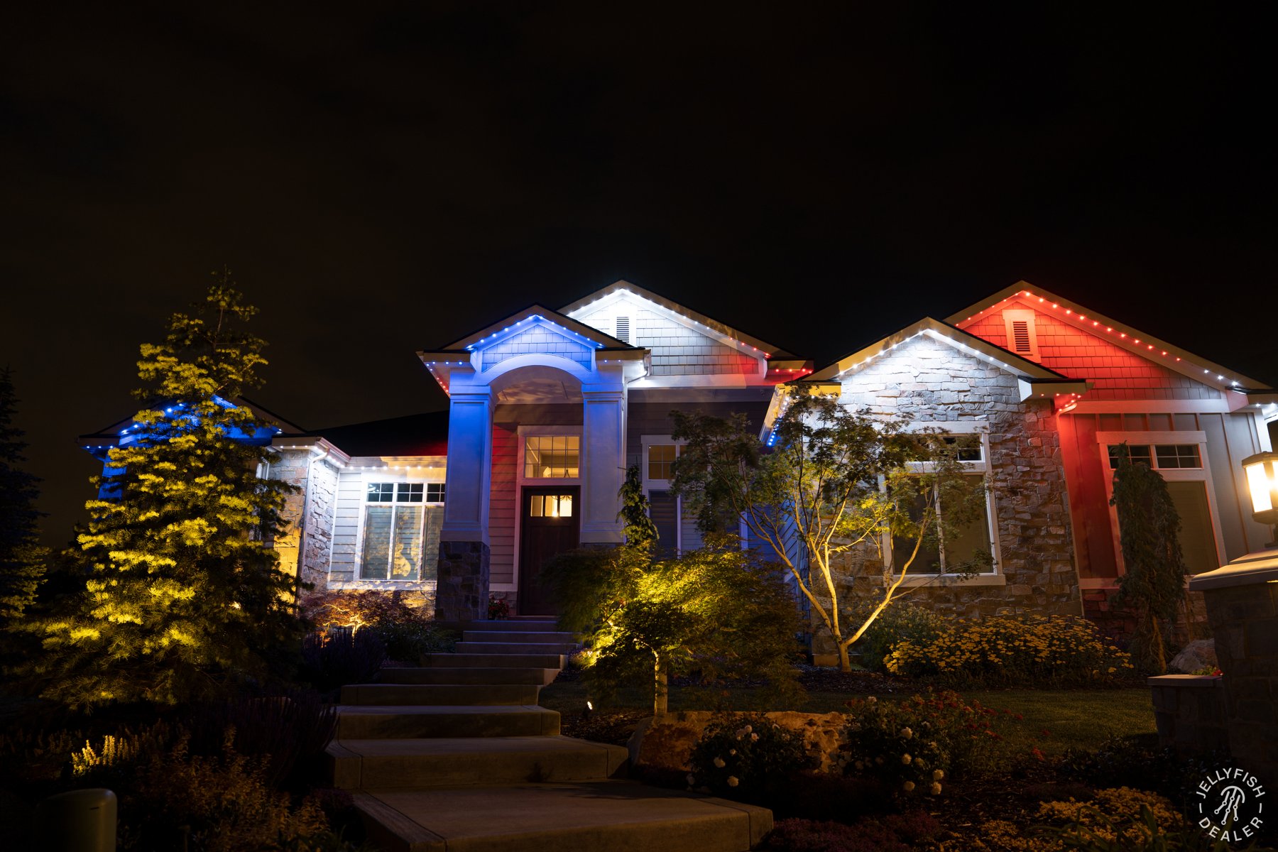 Patriotic lighting above a columned entry and surrounding garden.