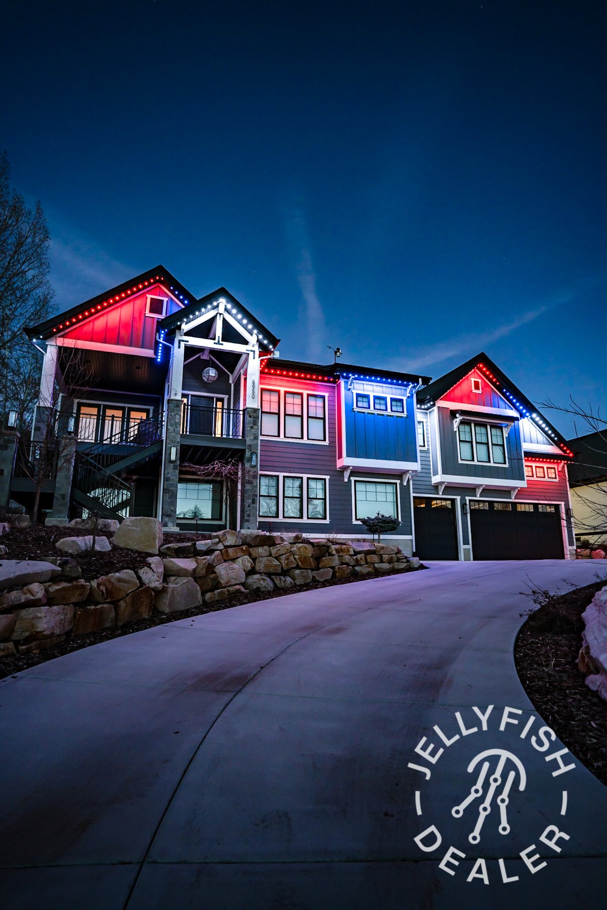 Patriotic roofline colors on a tall home at dusk.