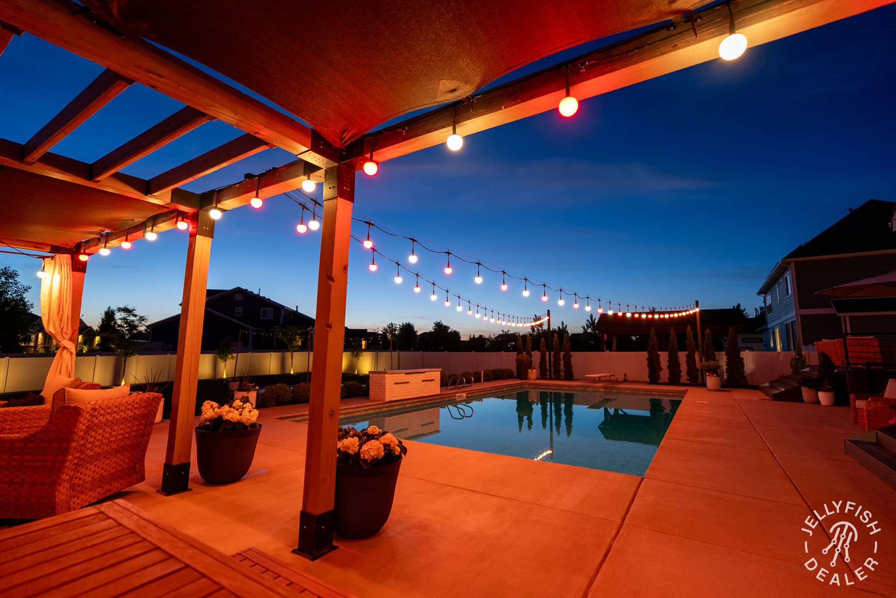 Warm and colored patio lights above a covered poolside seating area.
