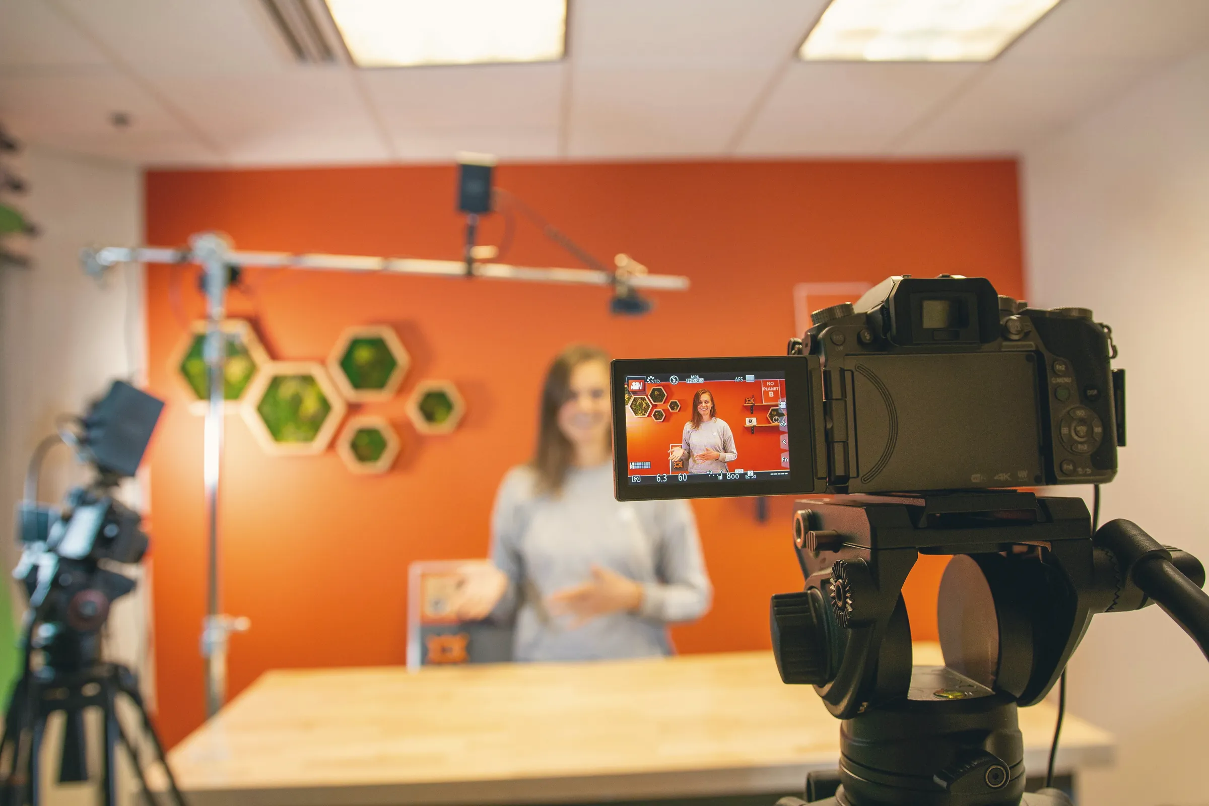 Camera filming a presenter in a bright studio
