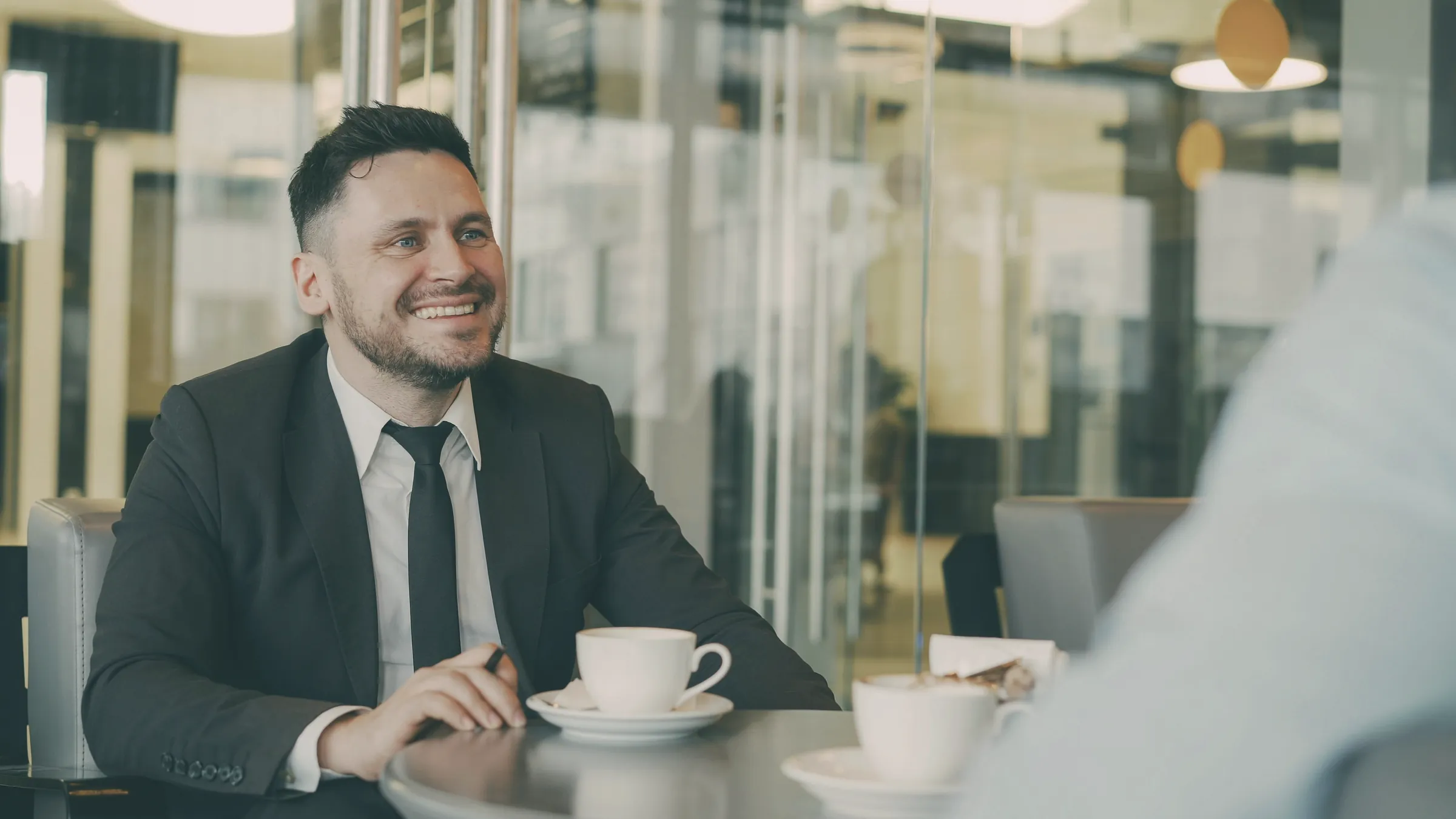 Man in a suit smiling over coffee