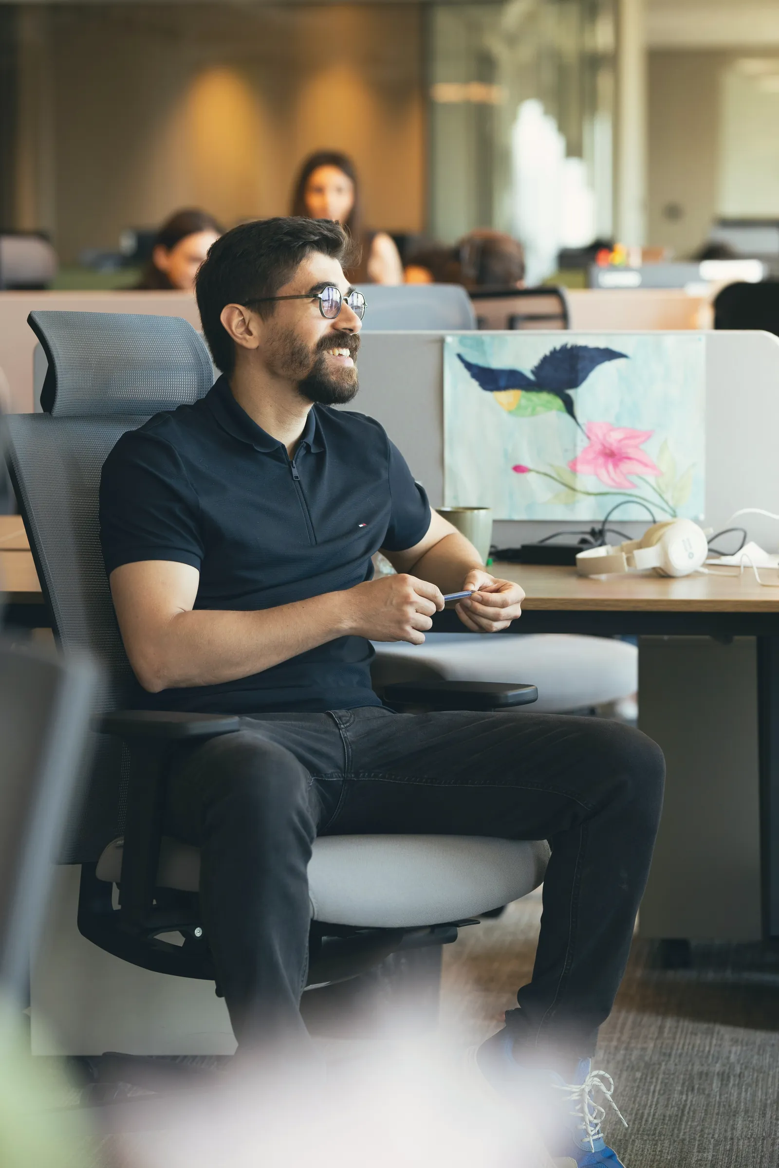 Man smiling at his desk in an open-plan office