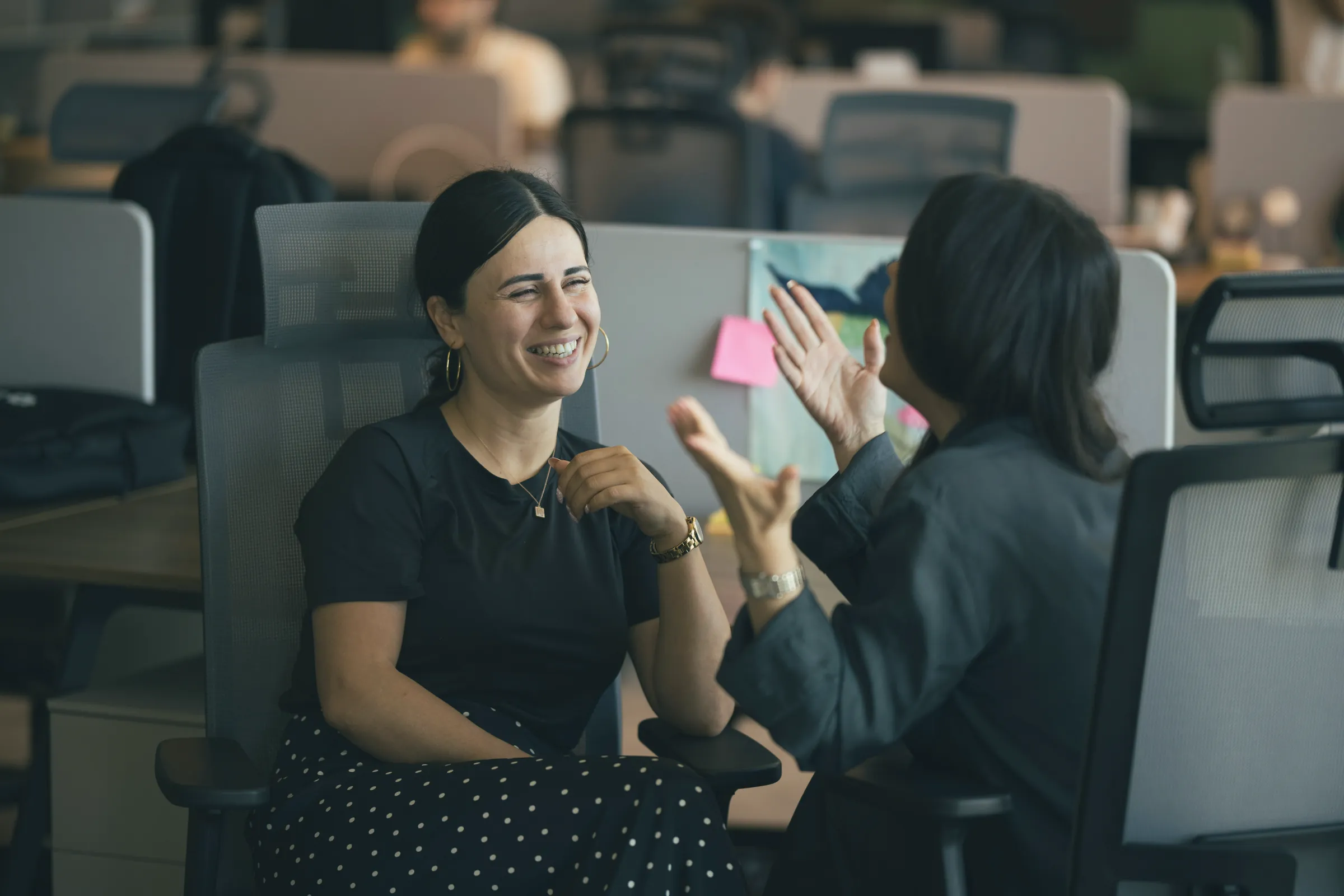 Two colleagues laughing together between desks