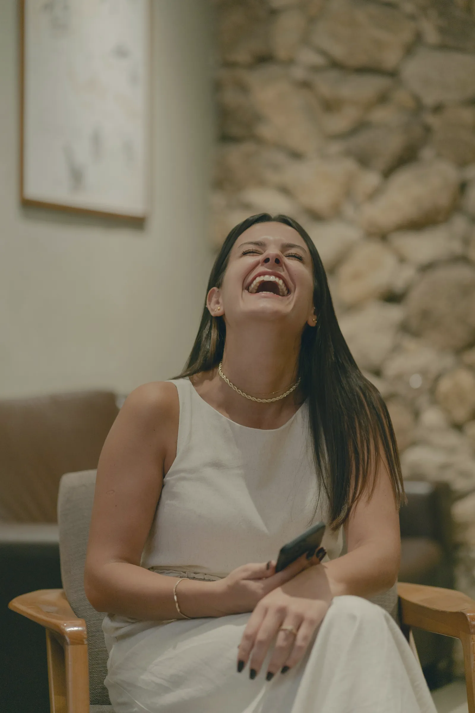 Woman laughing, seated in a relaxed space