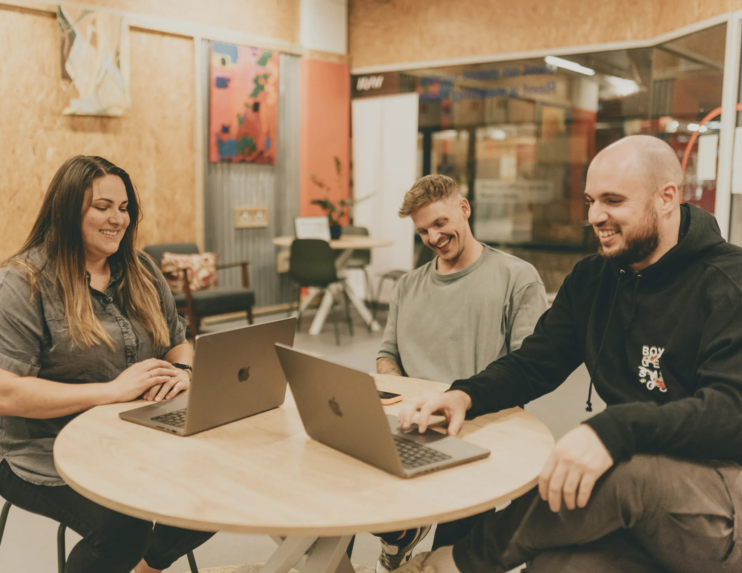 Three colleagues laughing while working on laptops