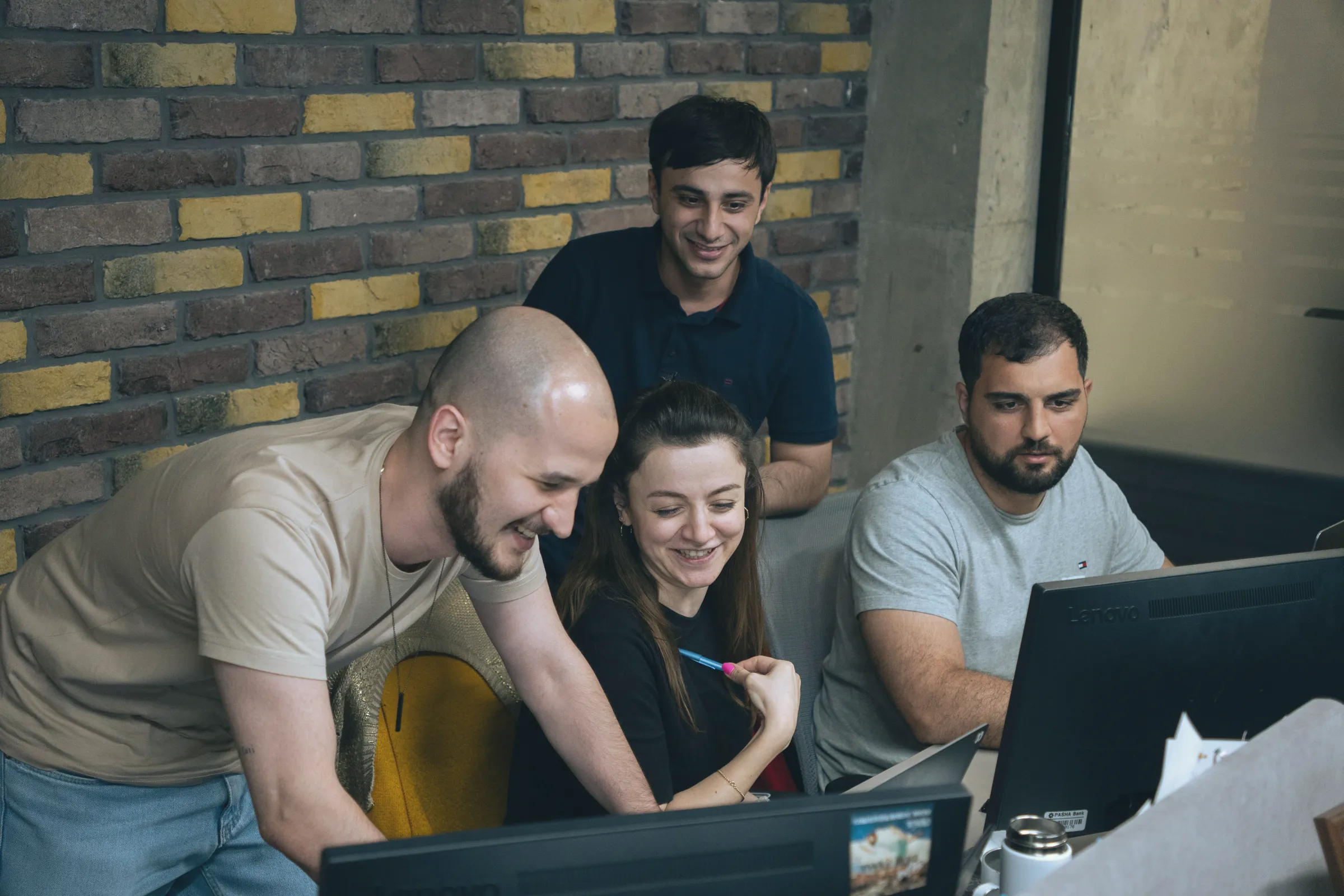 Team gathered around a screen, smiling