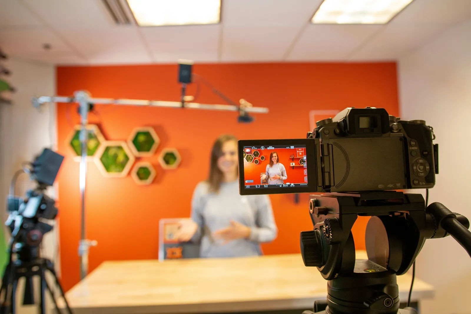 Camera filming a presenter in a bright studio