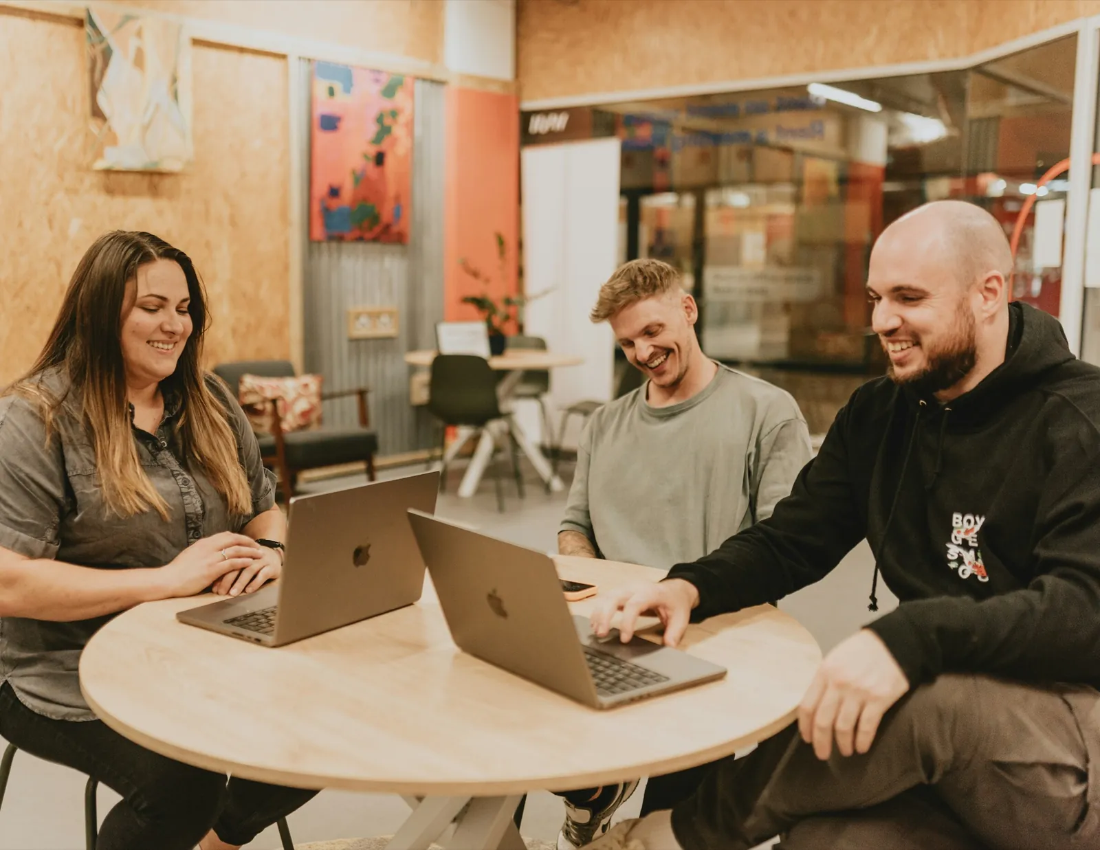 Three colleagues laughing while working on laptops