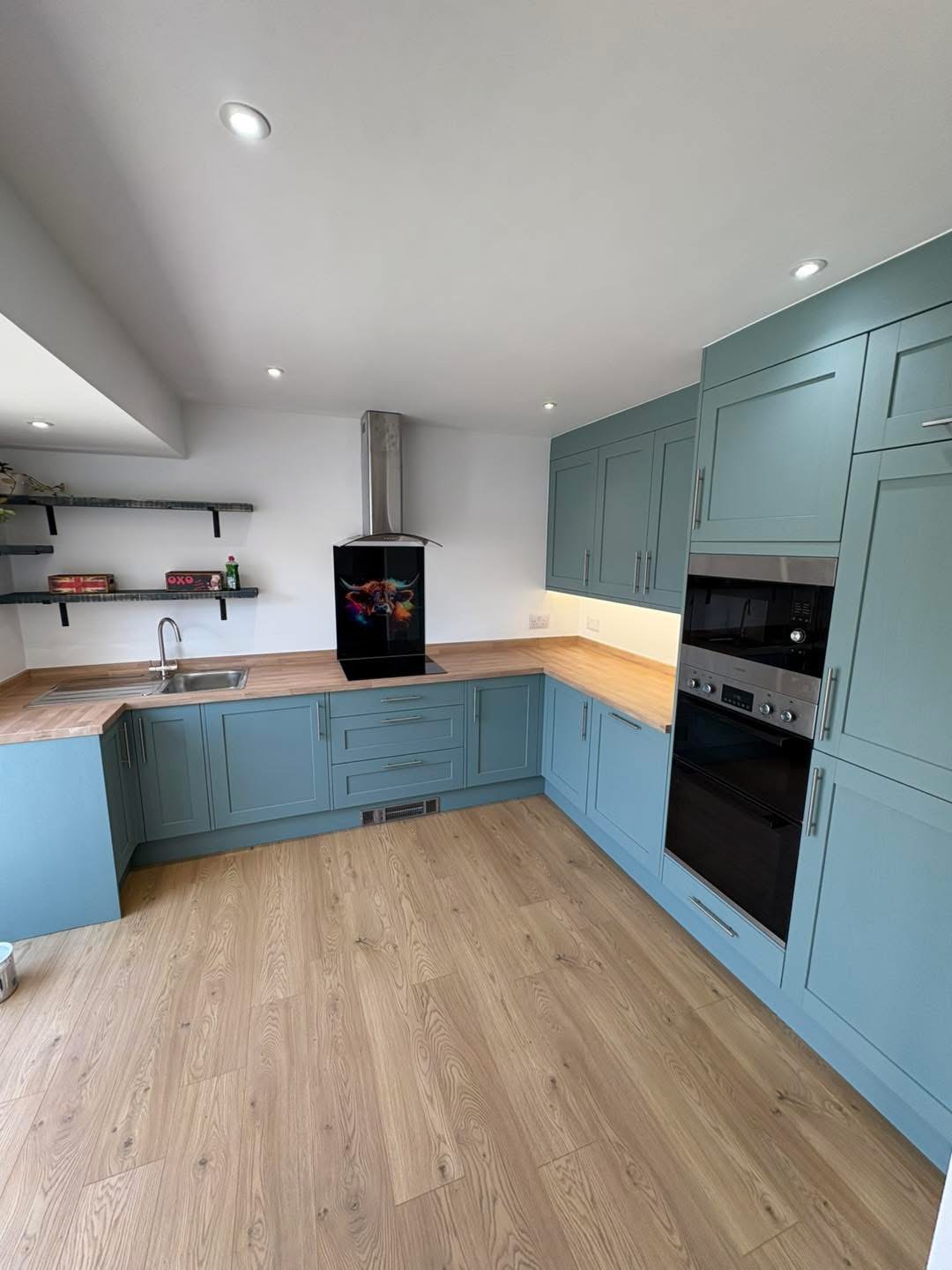 Completed blue kitchen with wood-effect flooring