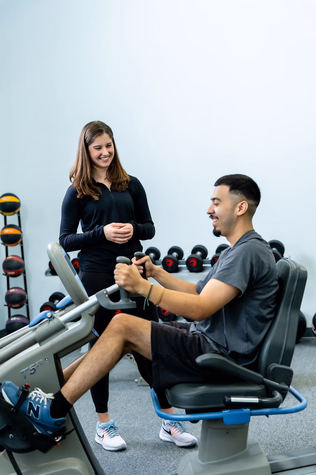 A NeuroBridge clinician guiding a patient on a recumbent stepper