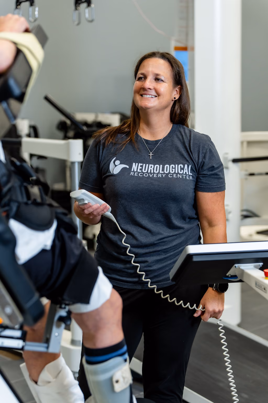 A smiling NeuroBridge clinician guiding a patient through robotic gait training