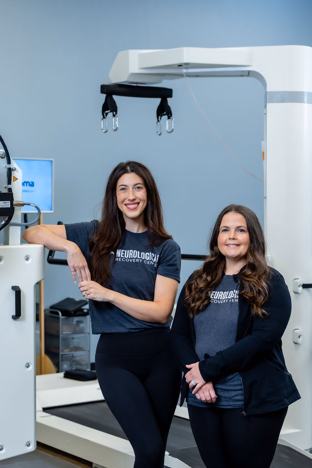Two smiling NeuroBridge clinicians in the rehabilitation gym