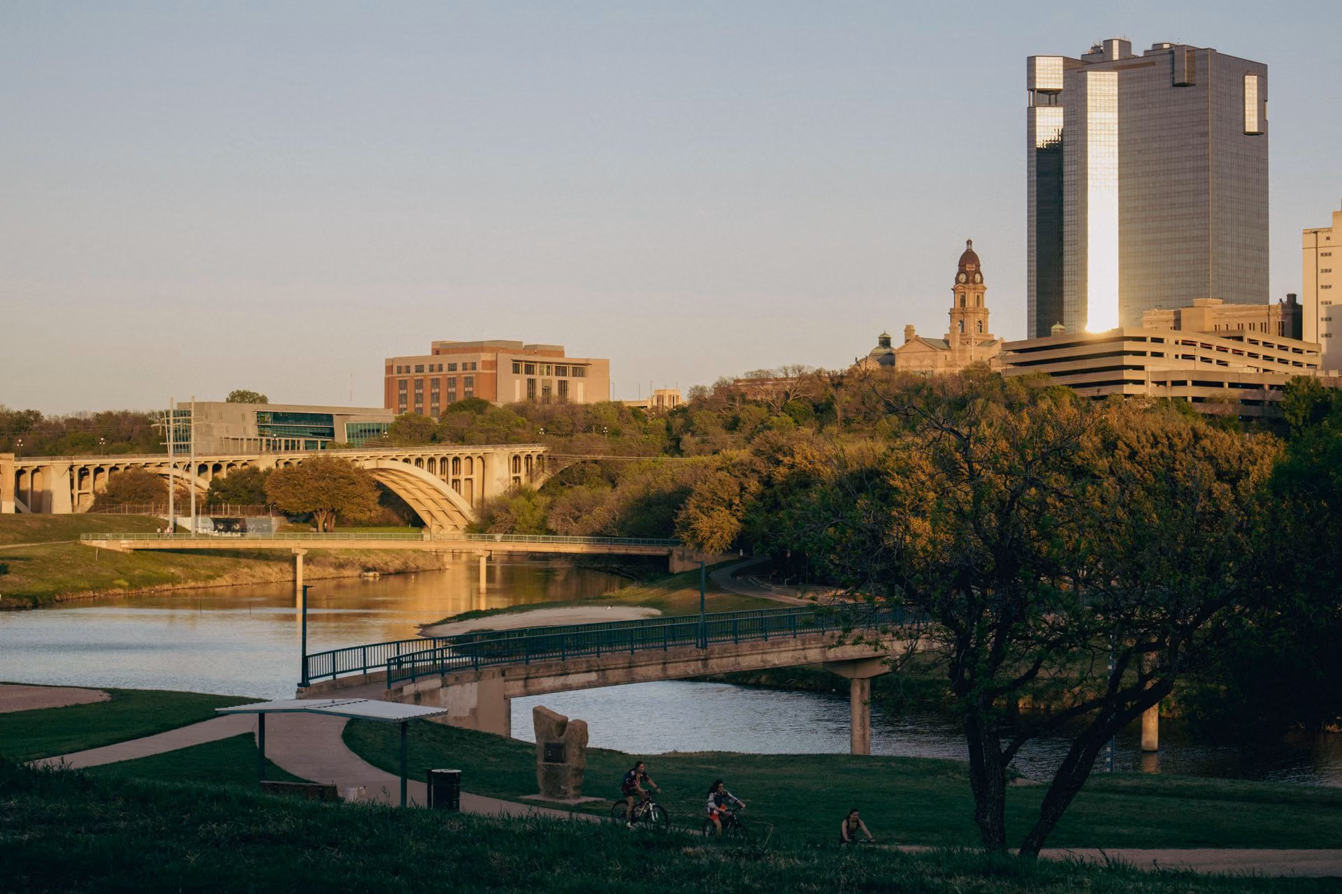 The Trinity River trail in Fort Worth at sunset, with the downtown skyline and courthouse beyond