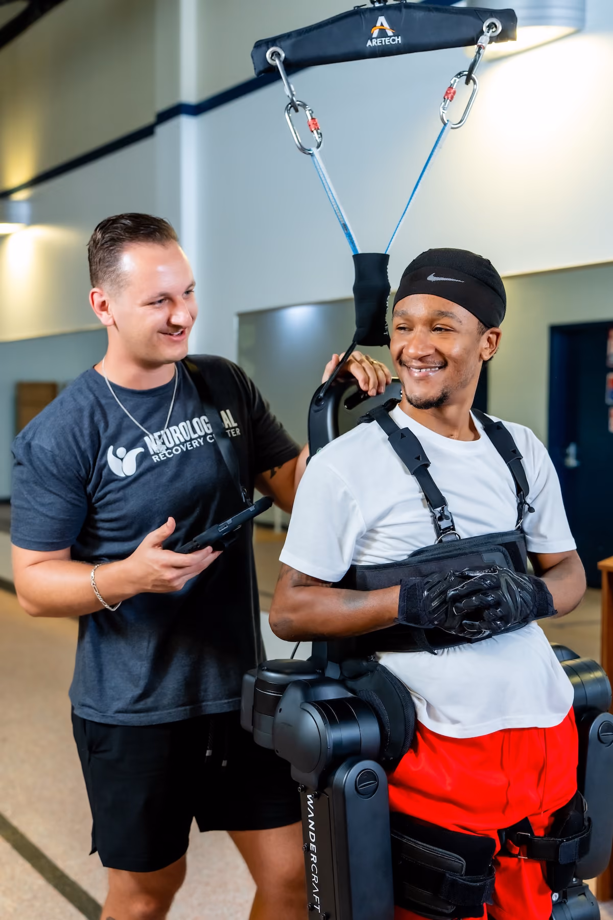 A patient walks in a robotic exoskeleton, supported and encouraged by three NeuroBridge clinicians