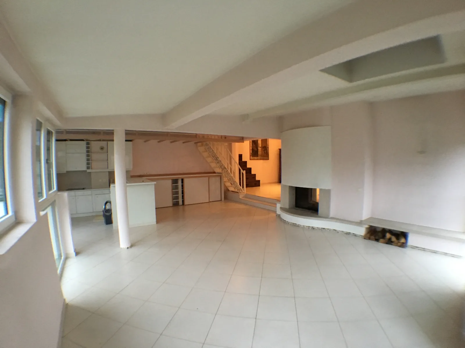 Avant travaux : pièce de vie avec carrelage clair, mezzanine et cheminée d'origine.
