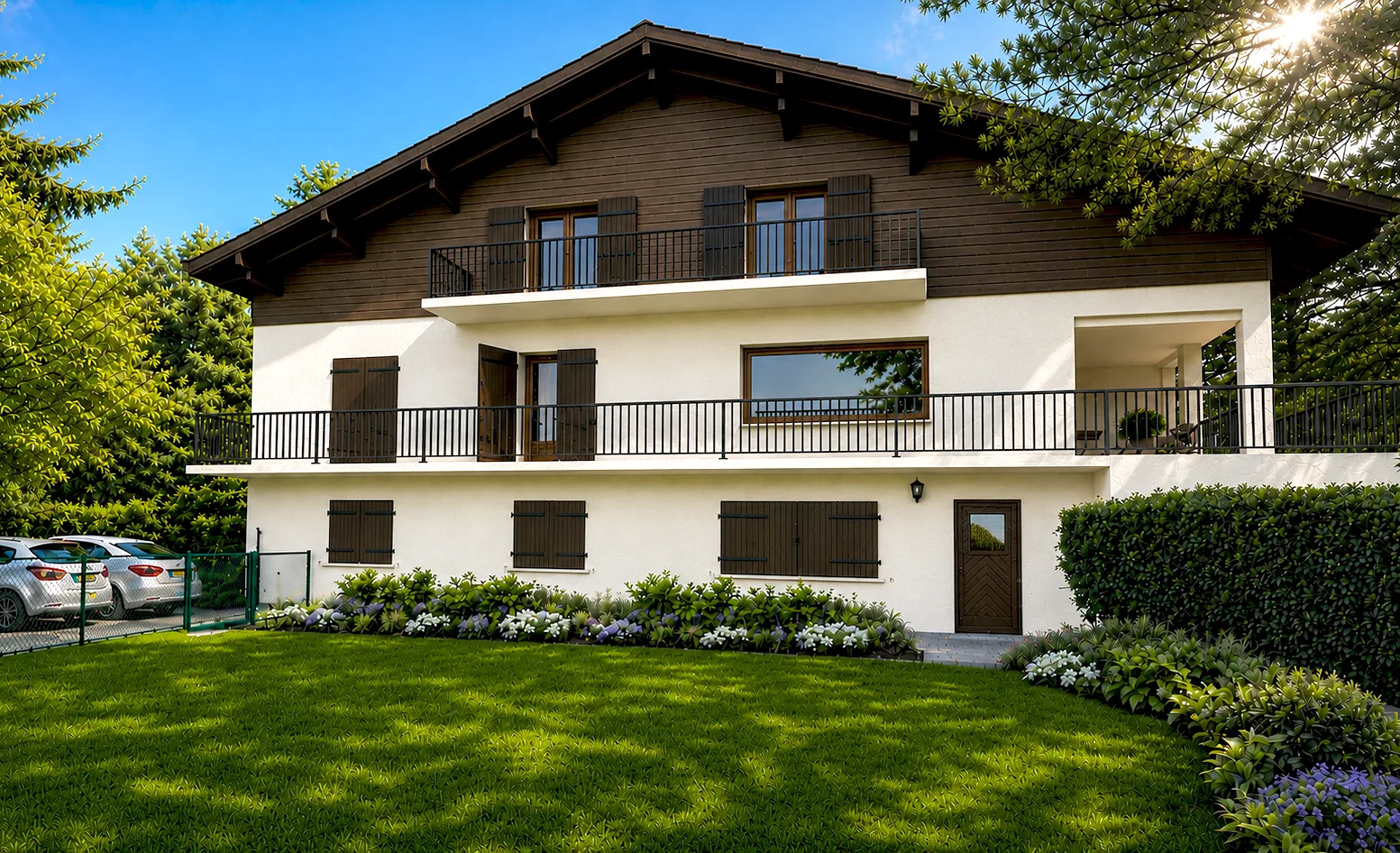 Façade du bâtiment après transformation, enduit blanc, bardage bois, volets et garde-corps sombres au-dessus d'un jardin.