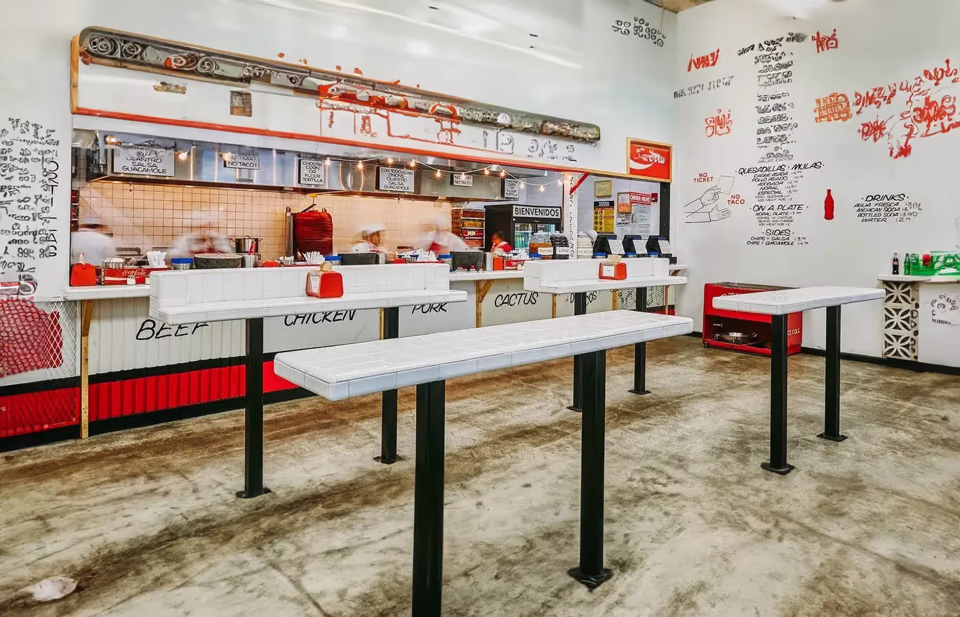Empty taqueria interior with an order counter and high tables