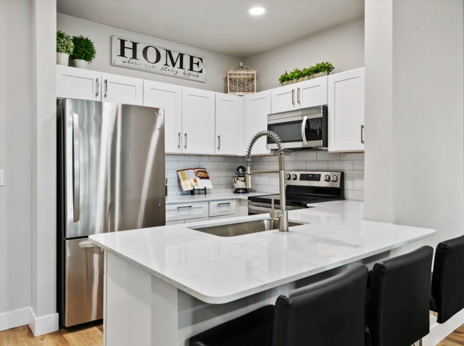 Colonial Court: Renovated unit kitchen with white shaker cabinets and quartz island