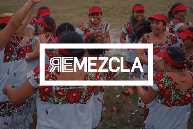 Group of women wearing traditional white dresses with red floral embroidery and red caps, dancing in a circle outdoors on grass, with the word 'REMEZCLA' overlaid in white framed text.