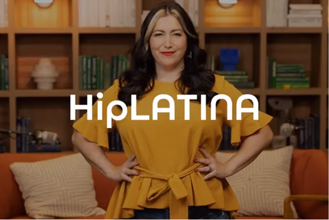 Woman with long dark hair wearing a yellow top with a belt tied at the waist standing confidently in front of a bookshelf and two cushioned chairs, with the word 'HipLATINA' overlaid across the center.