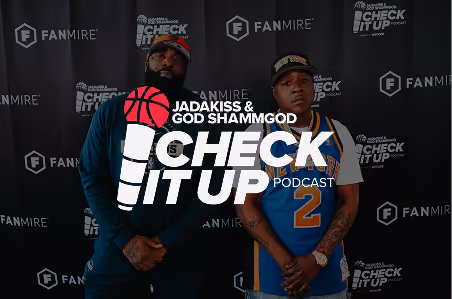 Two men standing in front of a black backdrop with the Fanmire and Check It Up Podcast logos; one man wears a dark jacket and hat, the other wears a blue basketball jersey and hat.