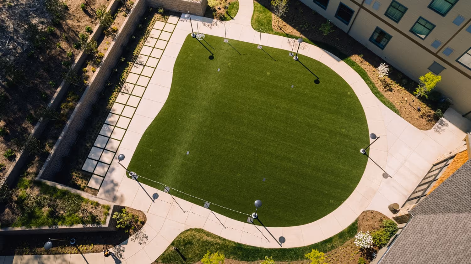 Aerial view of a landscaped courtyard with a curved walkway and green lawn at a hospitality property.