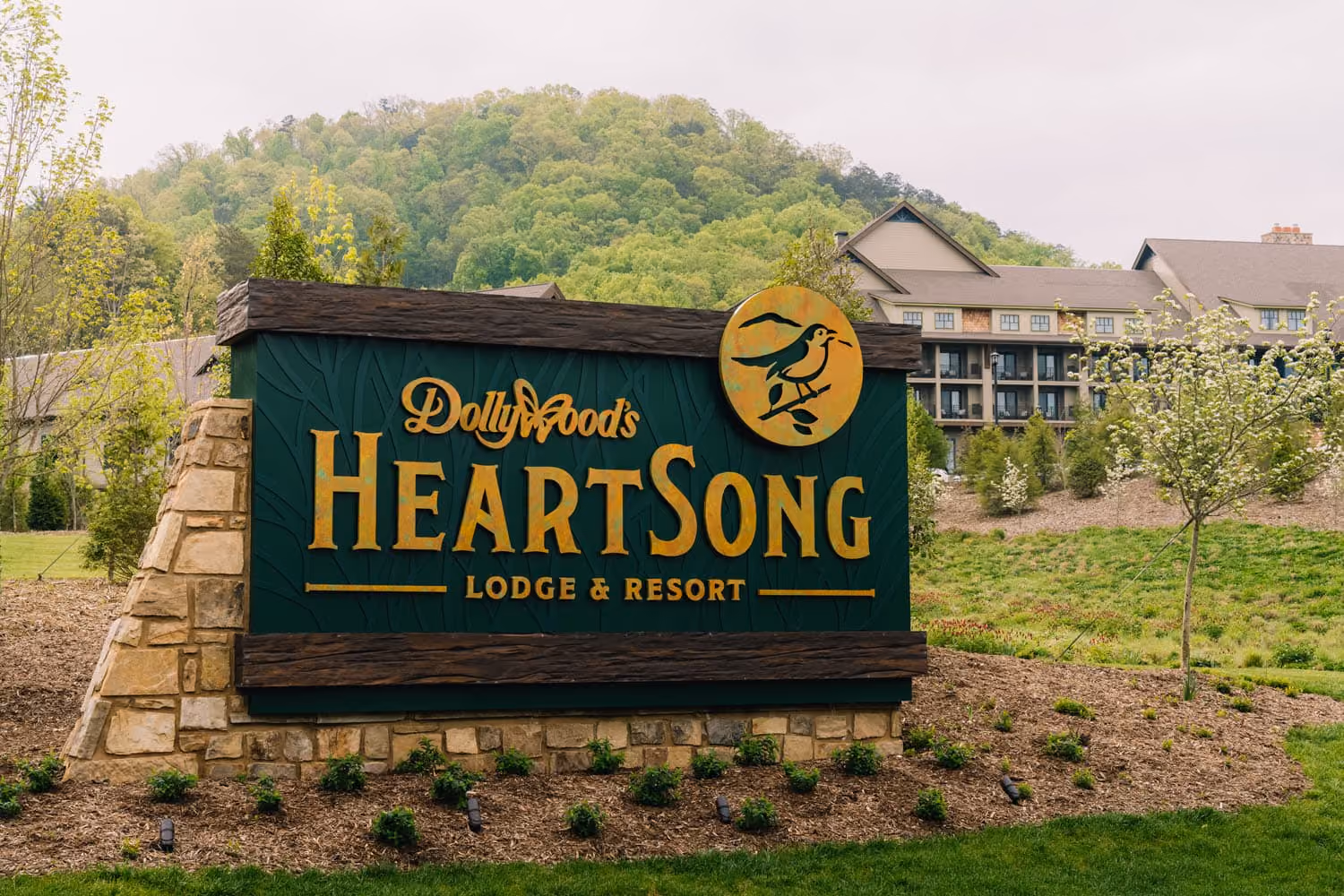 Dolly Parton’s HeartSong Lodge & Resort sign with wooded hills and a lodge in the background