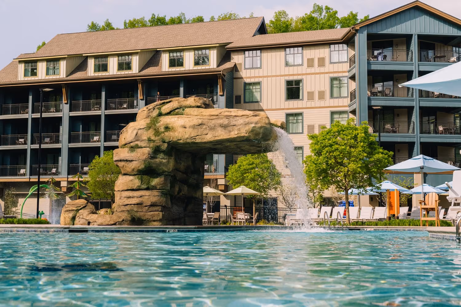 Resort pool with rock waterfall in front of a multi-story hospitality building