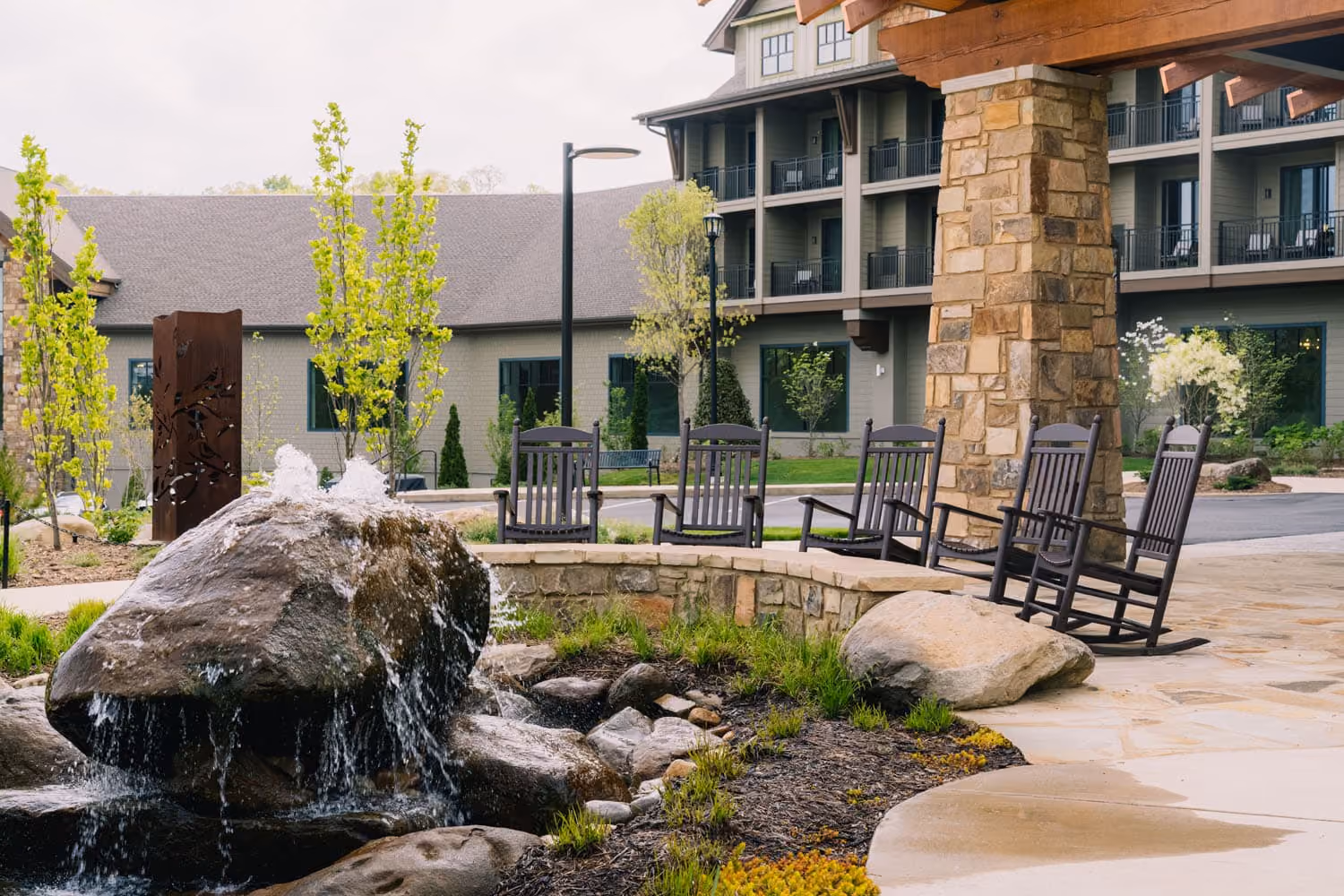 Rock fountain and rocking chairs outside a lodge-style hospitality building in Knoxville