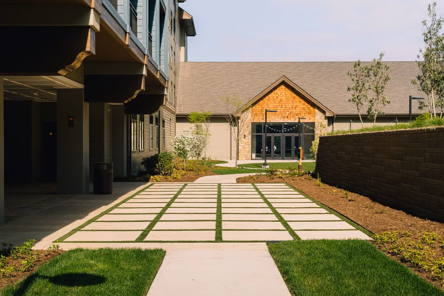 Modern hospitality building courtyard with stone paver walkway and landscaped entrance