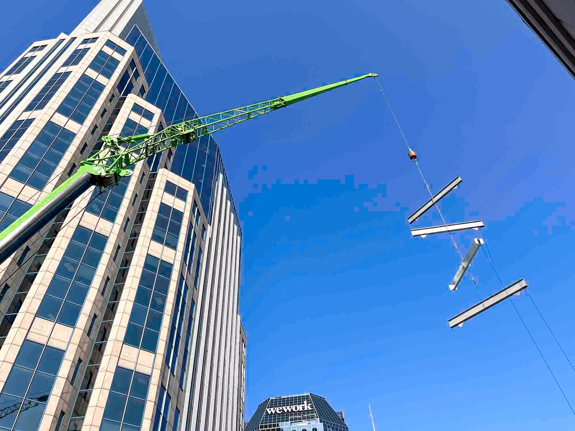 Crane lifting steel beams beside a high-rise under construction, with D&S Builders context.