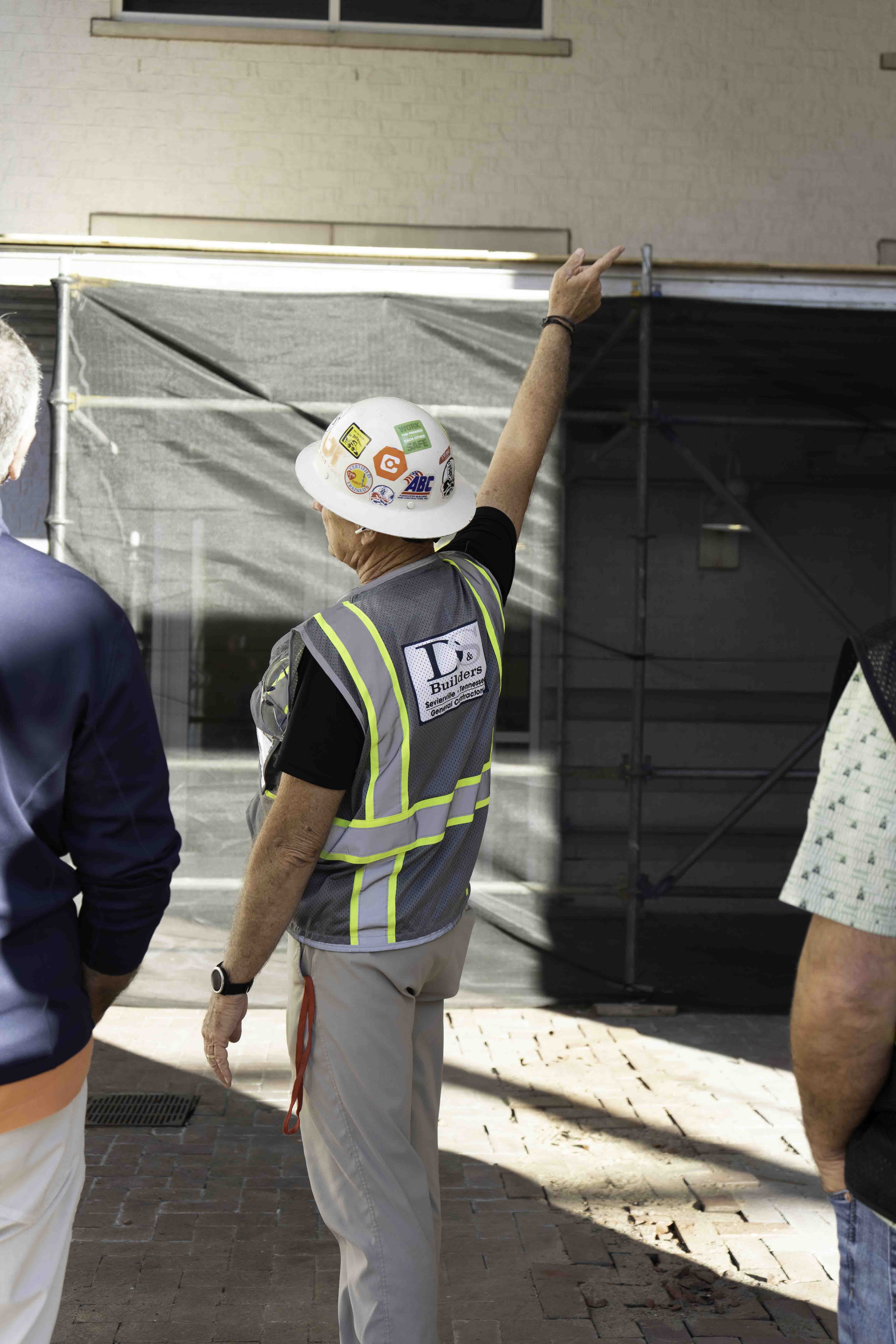 D&S Builders worker in hard hat and safety vest pointing at a construction site