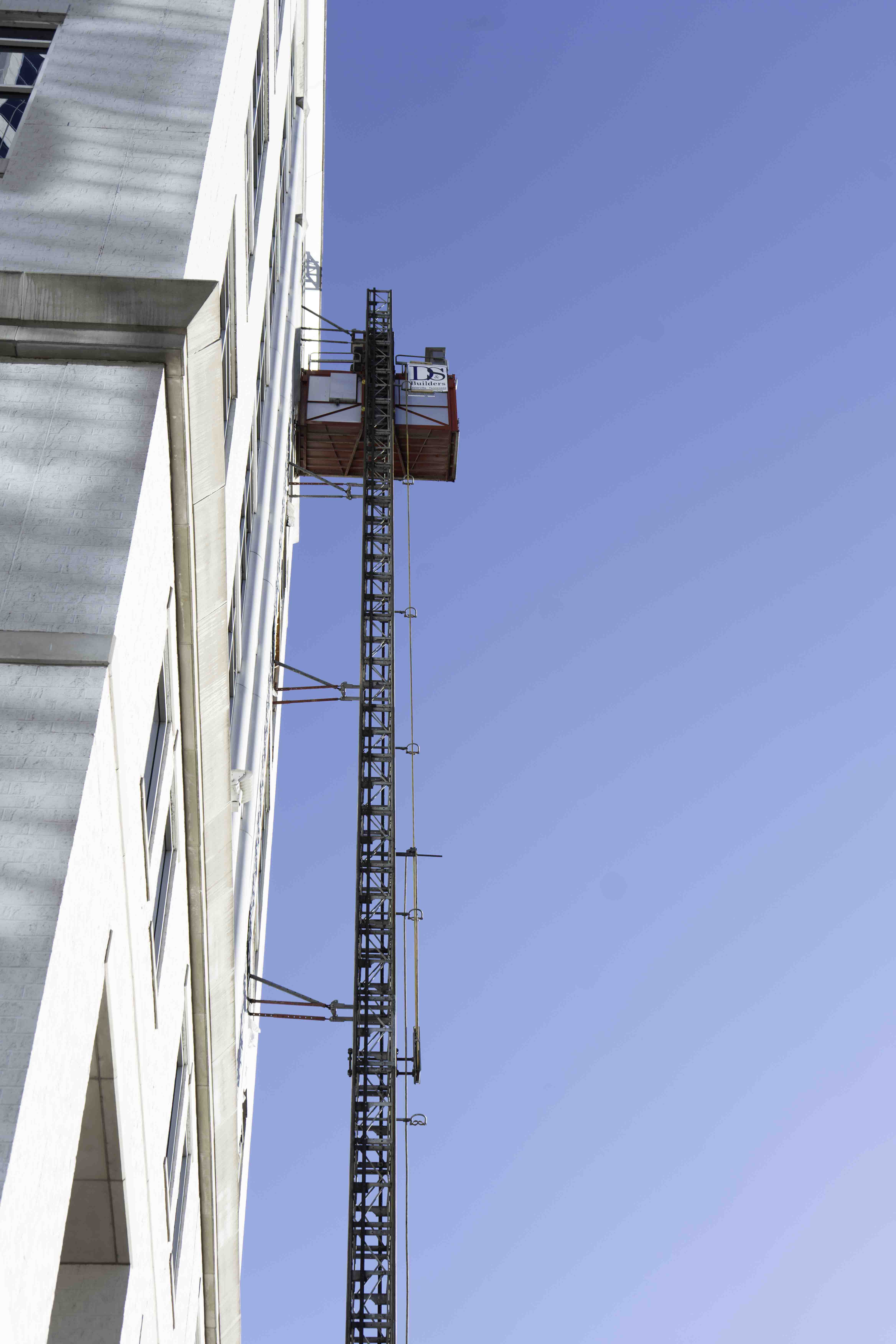 Construction hoist beside a building against a clear blue sky