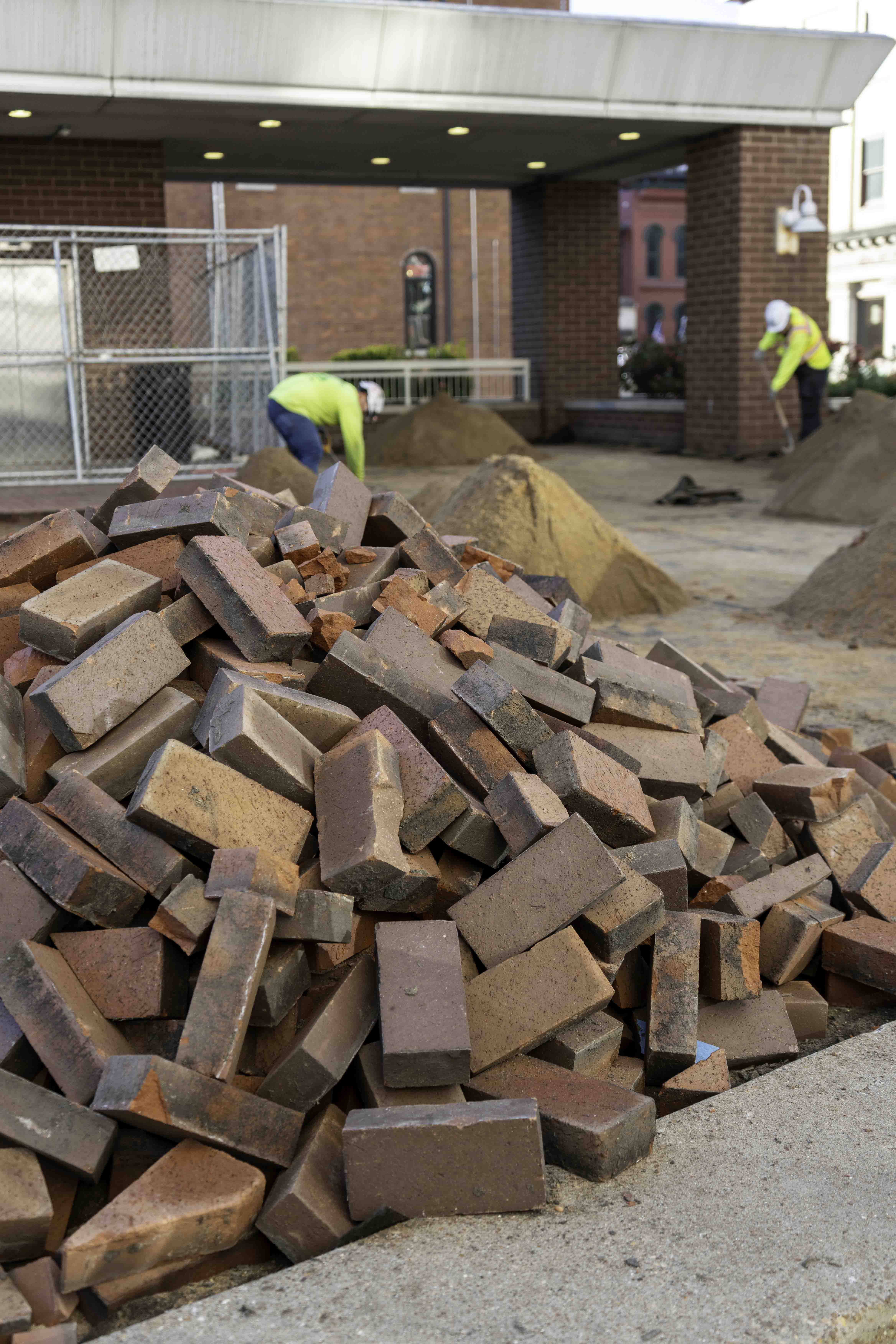 Pile of bricks at a construction site with workers in the background