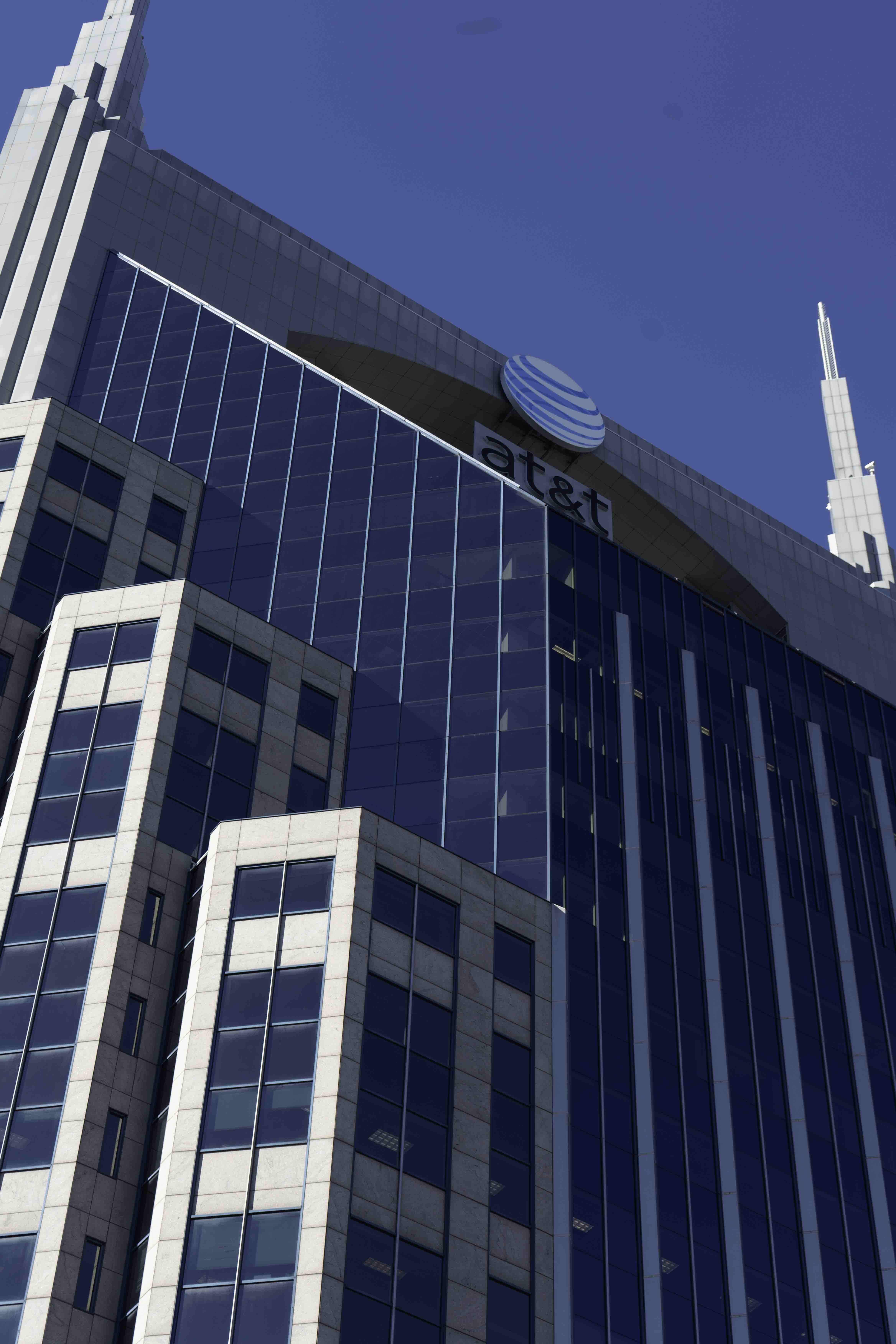 Modern glass office tower with AT&T logo against a clear blue sky