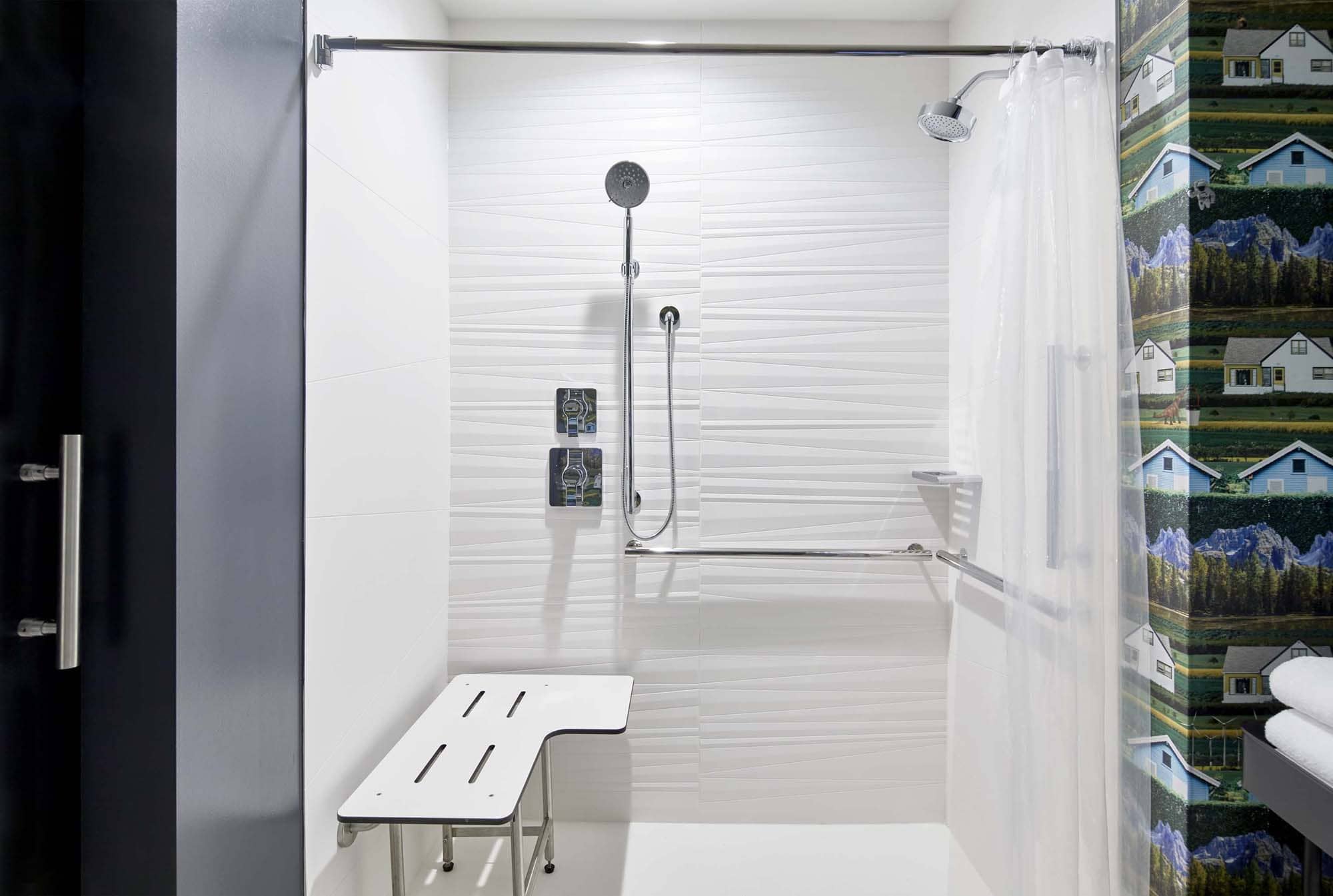 Accessible shower with grab bars and a fold-down seat in a modern bathroom by D&S Builders