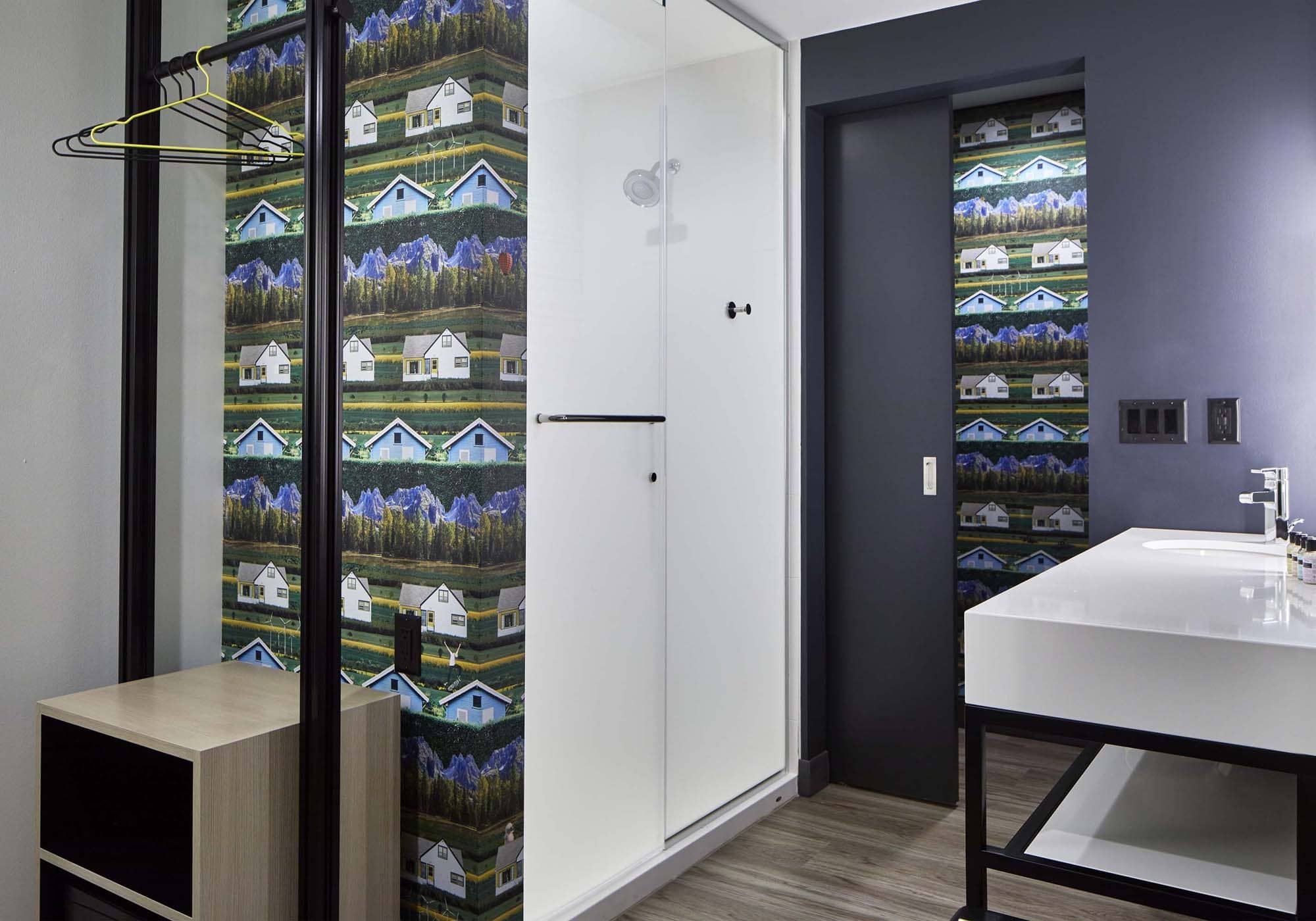 Modern bathroom with patterned wallpaper, white vanity, and walk-in shower in a D&S Builders project