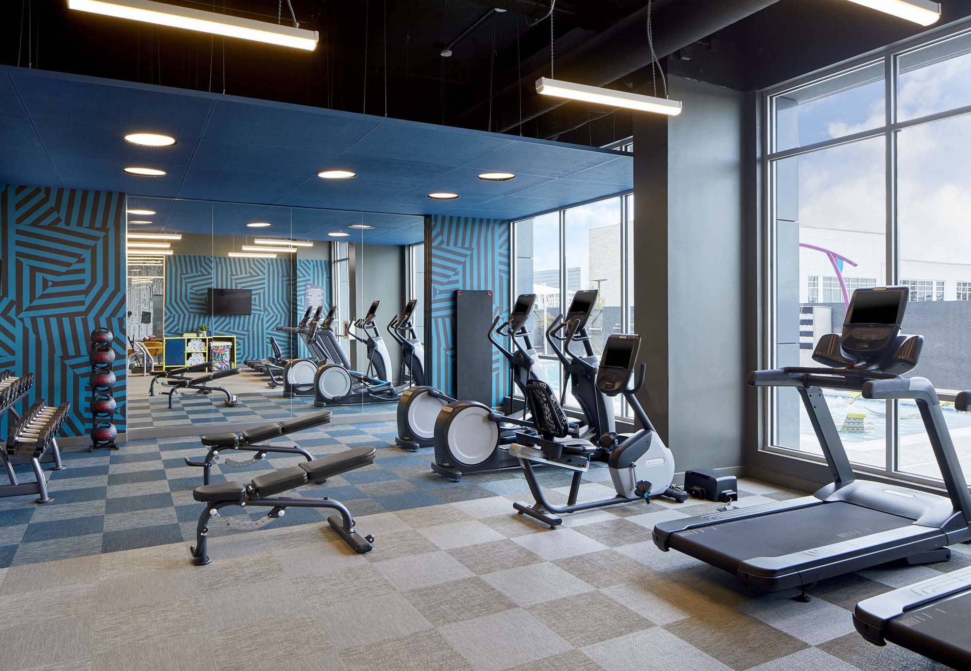 Modern hotel gym with treadmills, ellipticals, and weight benches