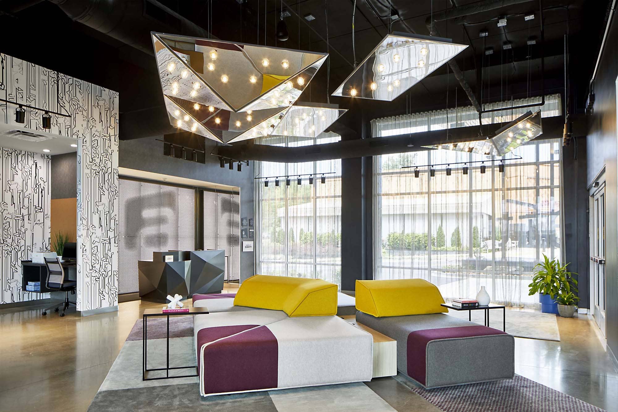 Modern hotel lobby with geometric pendant lights and colorful modular seating
