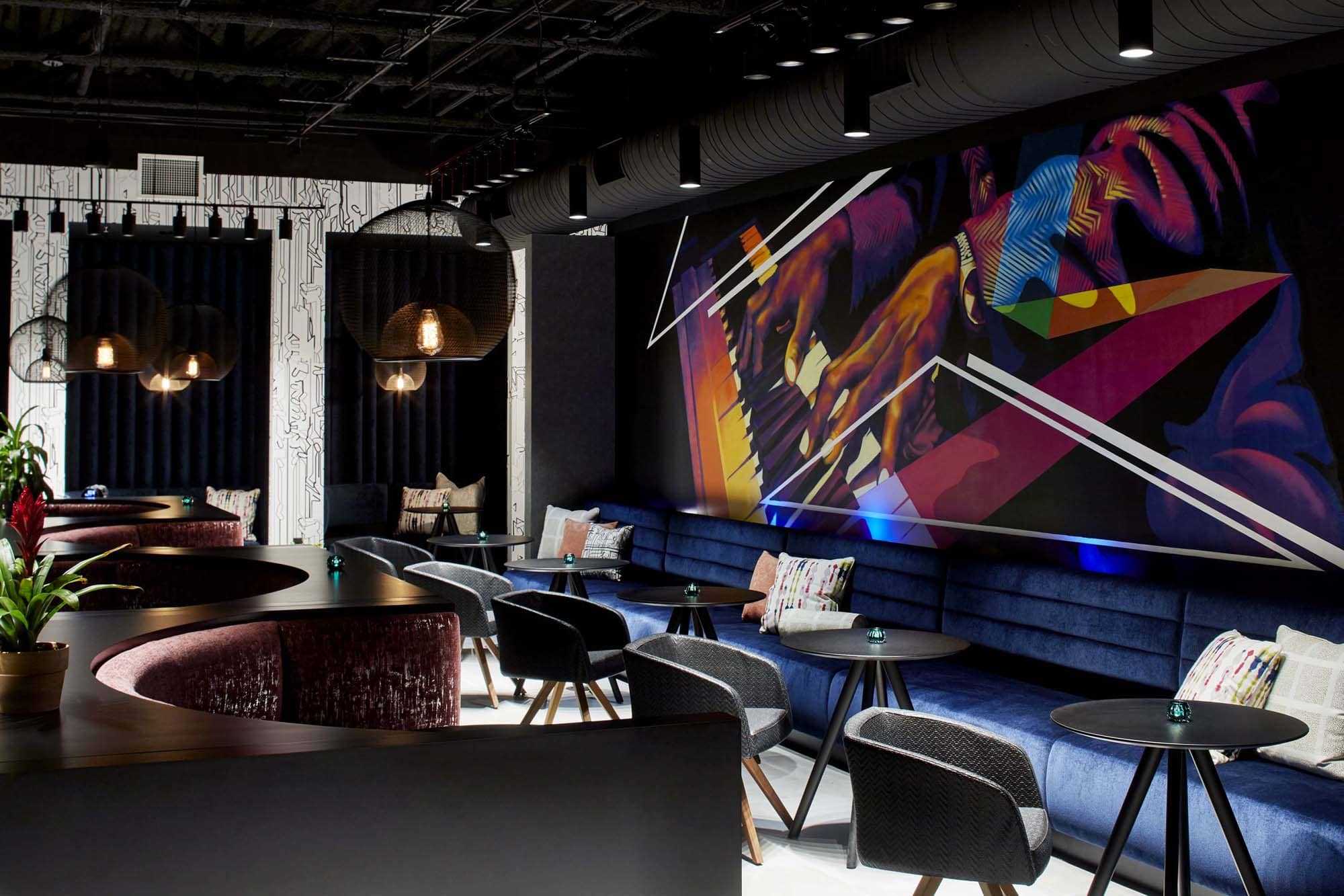 Stylish hospitality lounge with colorful mural, pendant lights, and seating