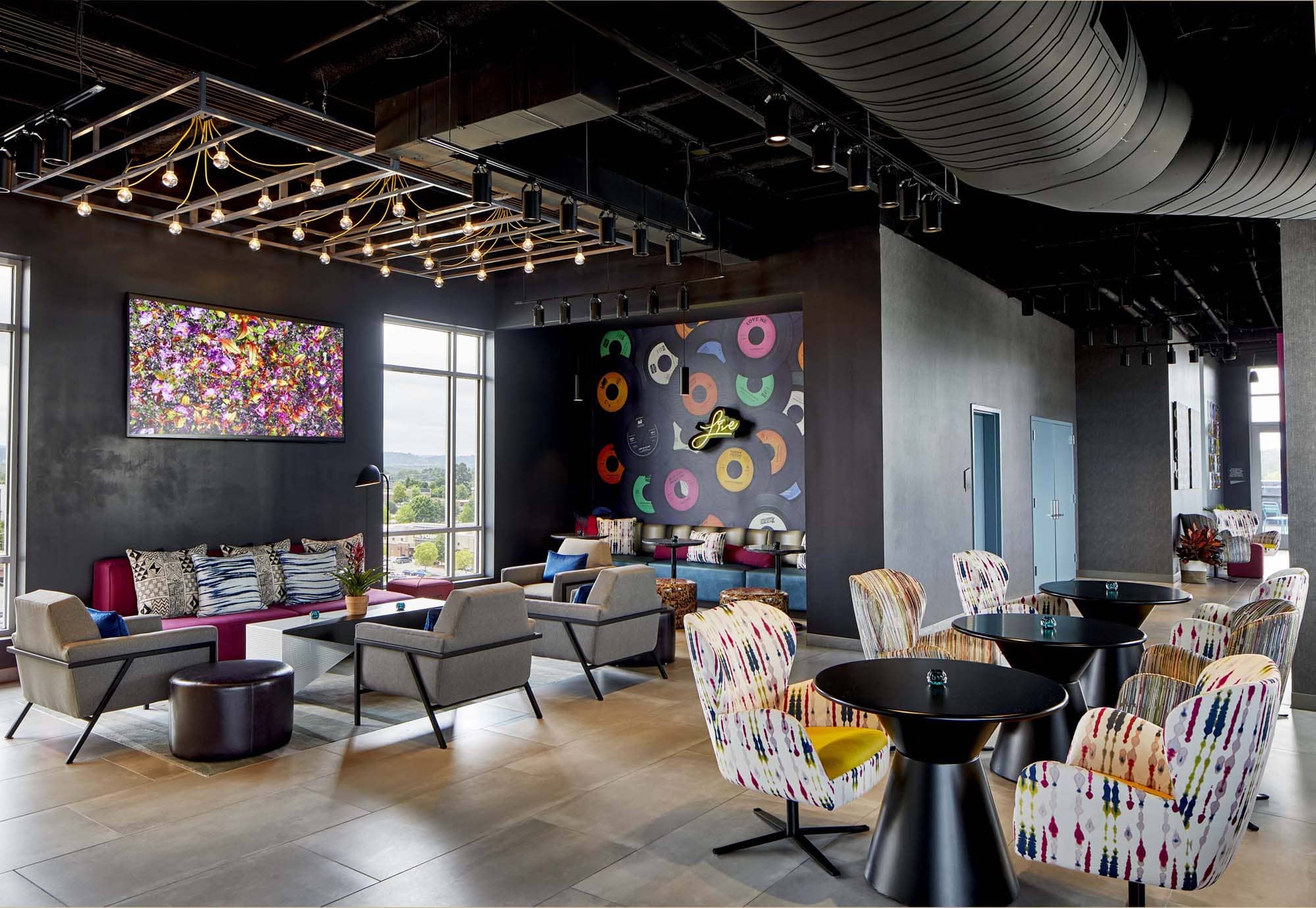 Modern hospitality lounge with colorful seating, artwork, and pendant lighting
