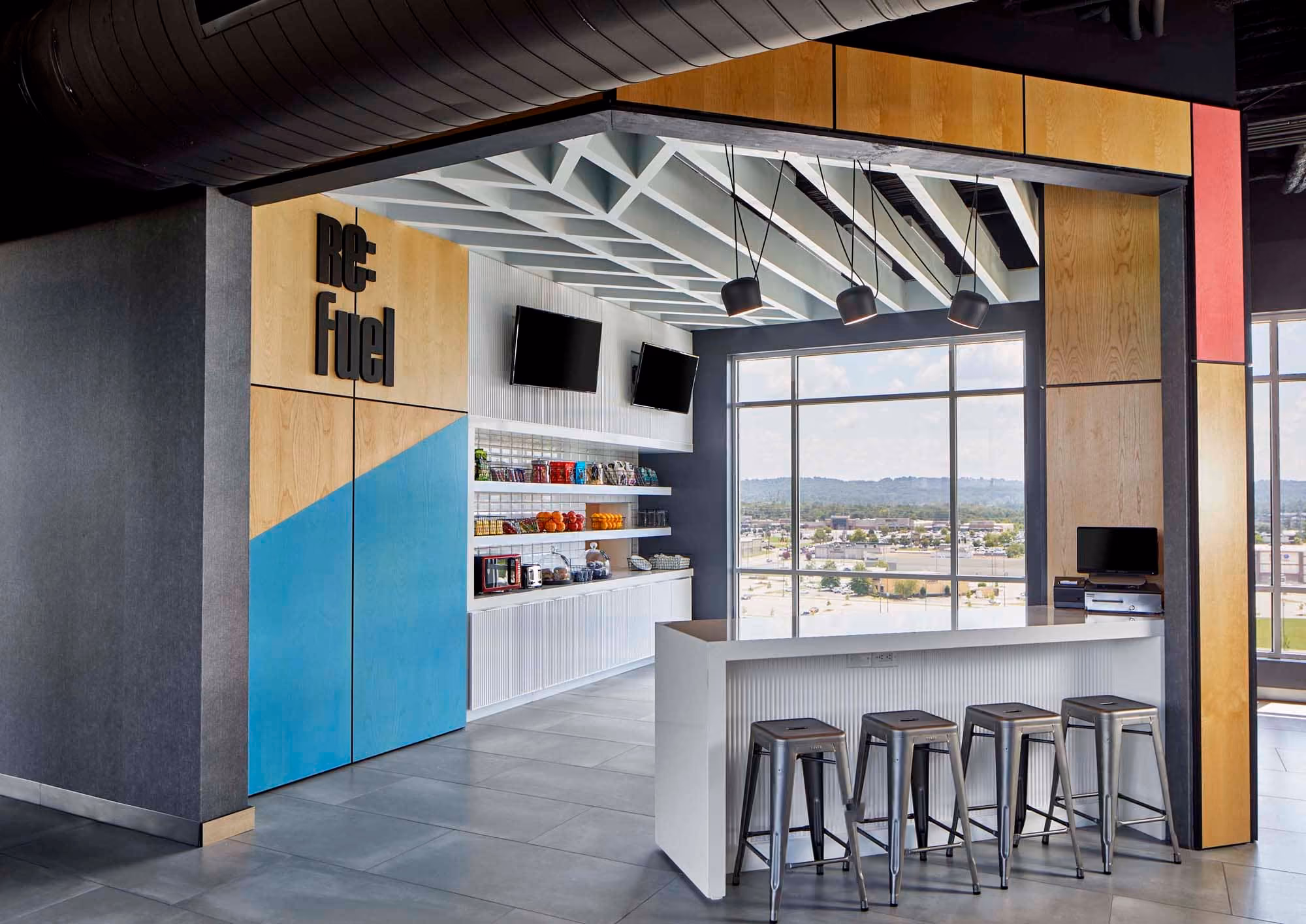 Modern hospitality lounge with bar stools, shelving, and large windows overlooking Knoxville.