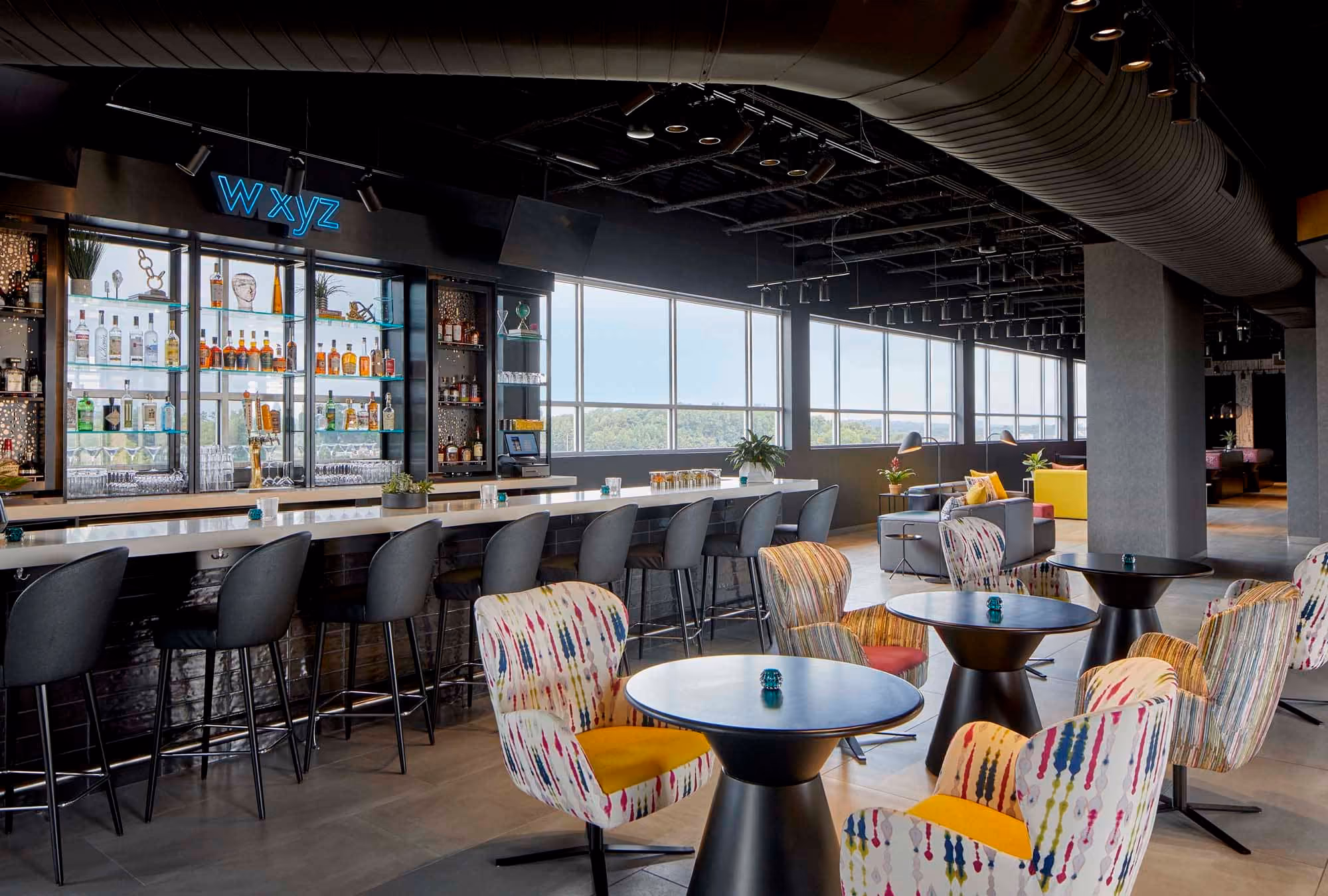 Modern hotel bar and lounge with colorful chairs and large windows