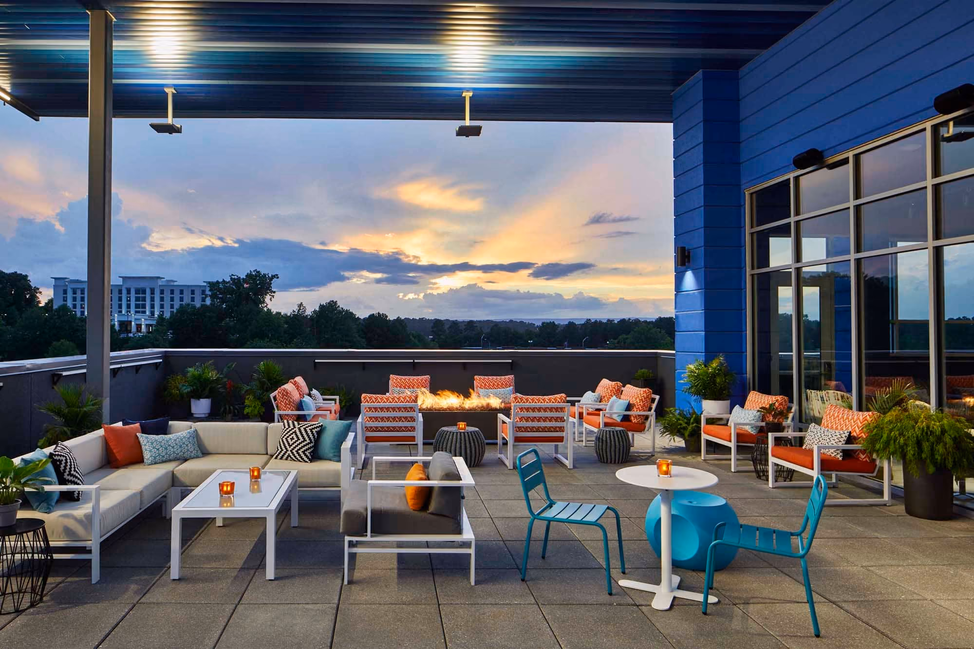 Rooftop hospitality patio with lounge seating and fire pit at sunset