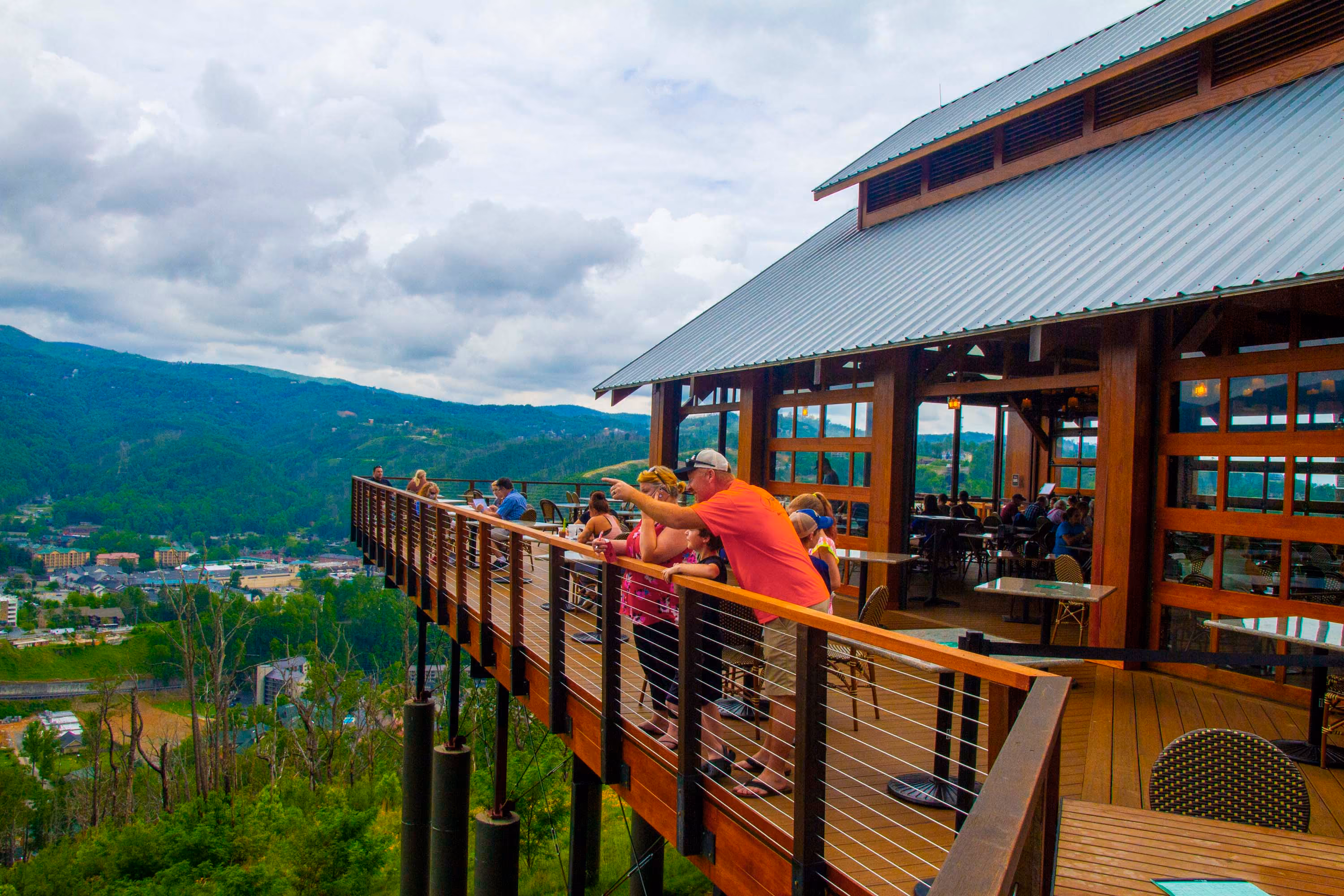 Scenic mountain-view deck at a hospitality venue with guests overlooking the valley