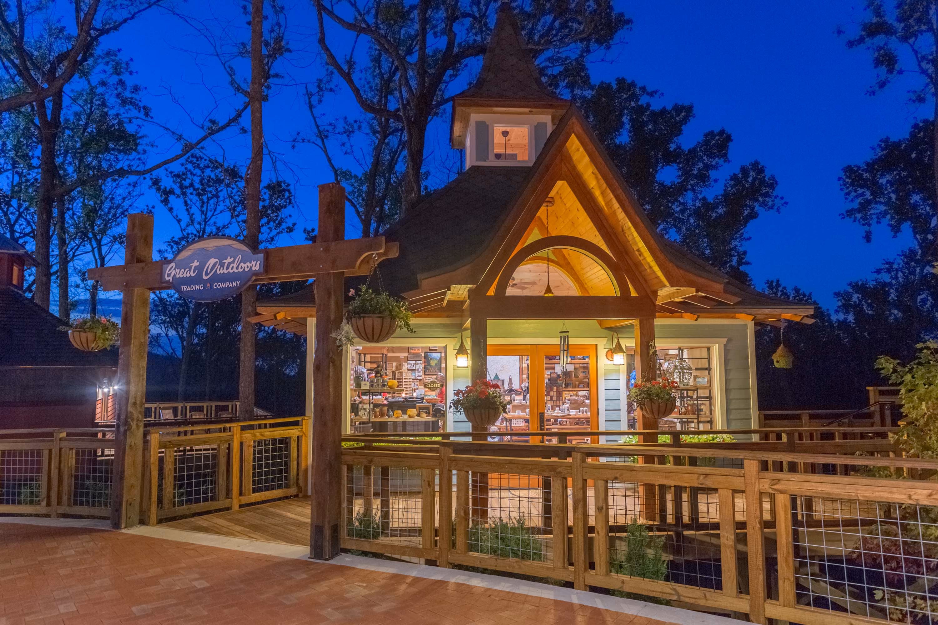 Lit-up rustic storefront with a wooden entrance and deck at dusk, built by D&S Builders.